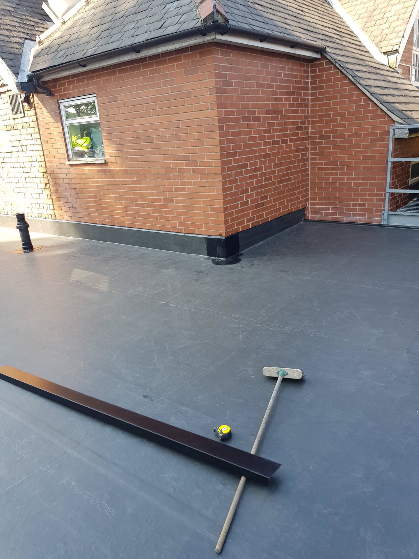 Completed flat roof with grey EPDM rubber membrane and brick extension with tiled pitched roof