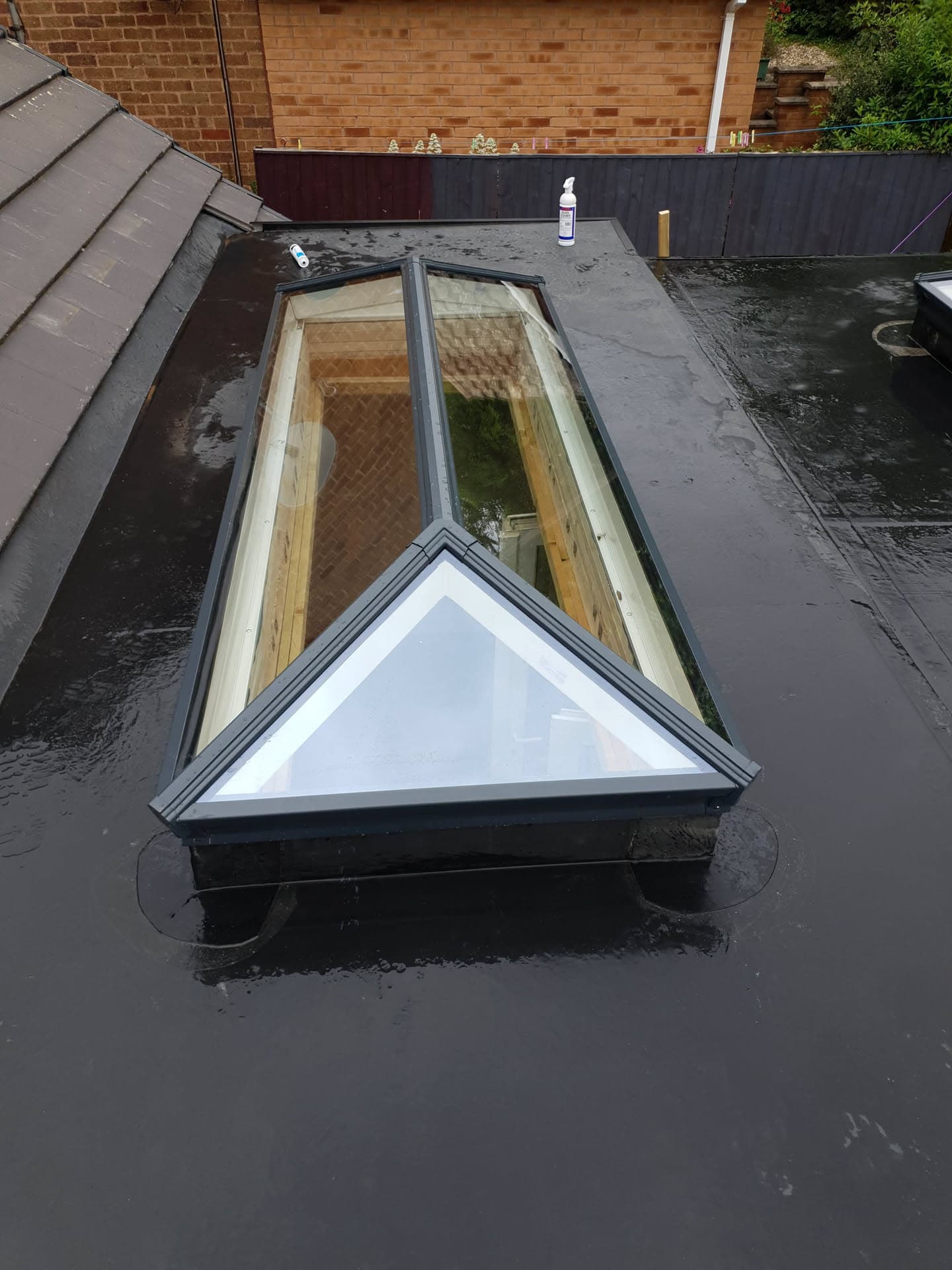 Flat roof with lantern skylight and dark felt covering beside tiled pitched roof