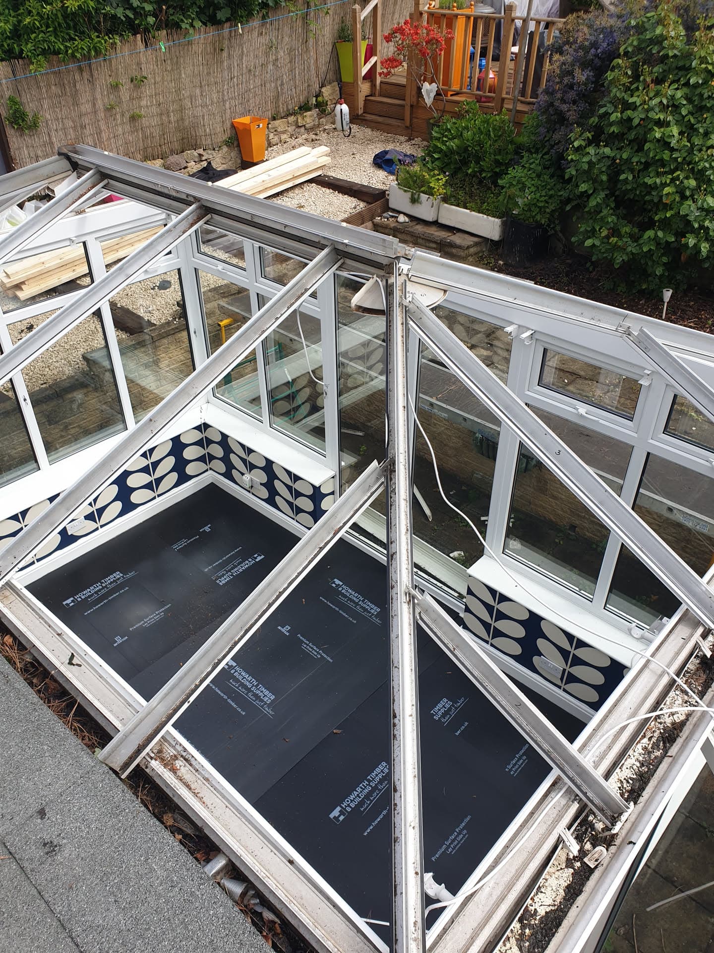 White uPVC conservatory roof frame with anthracite flat roof panels during installation