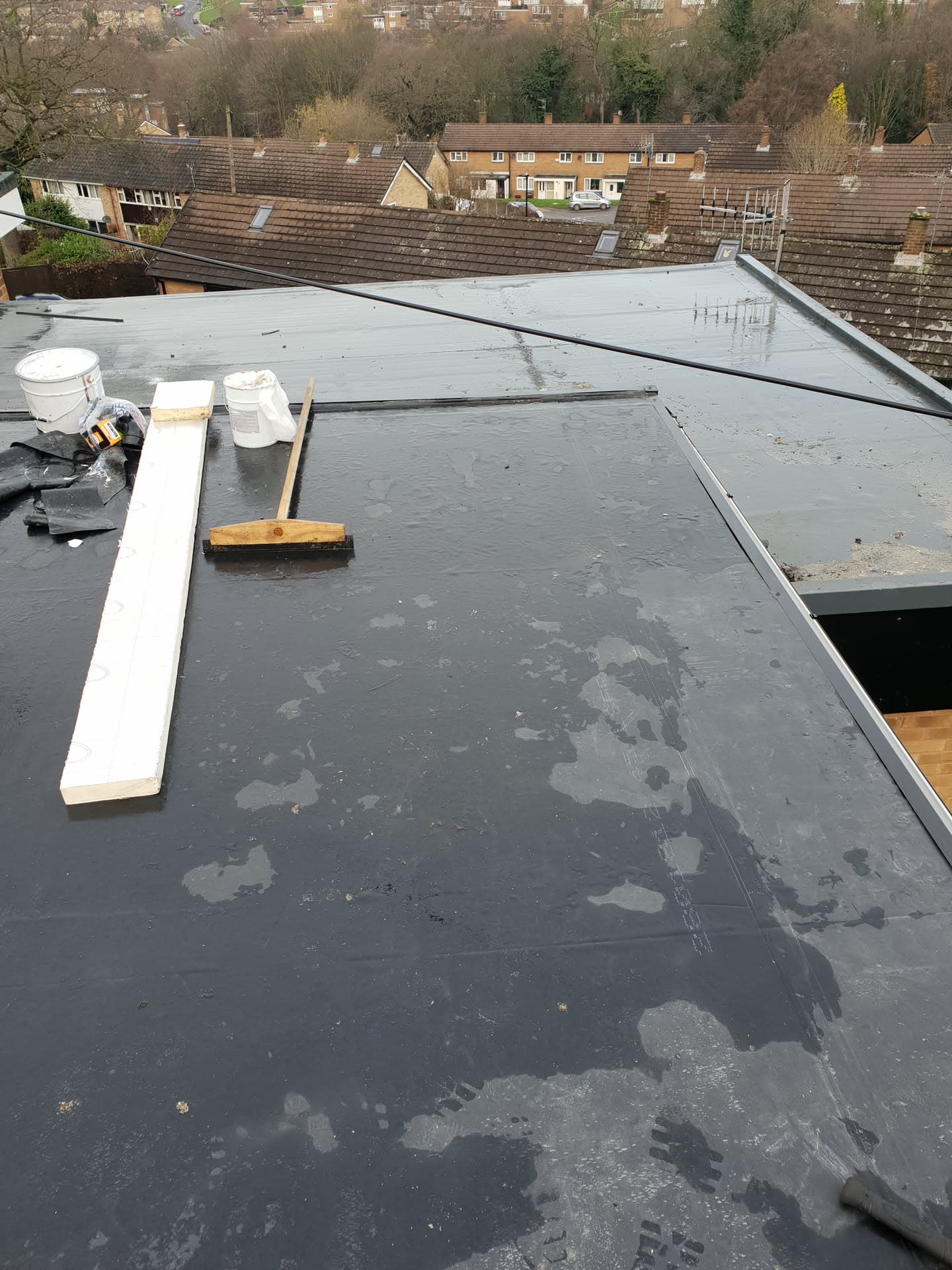 Flat roof with grey felt membrane in progress with tools and materials on surface