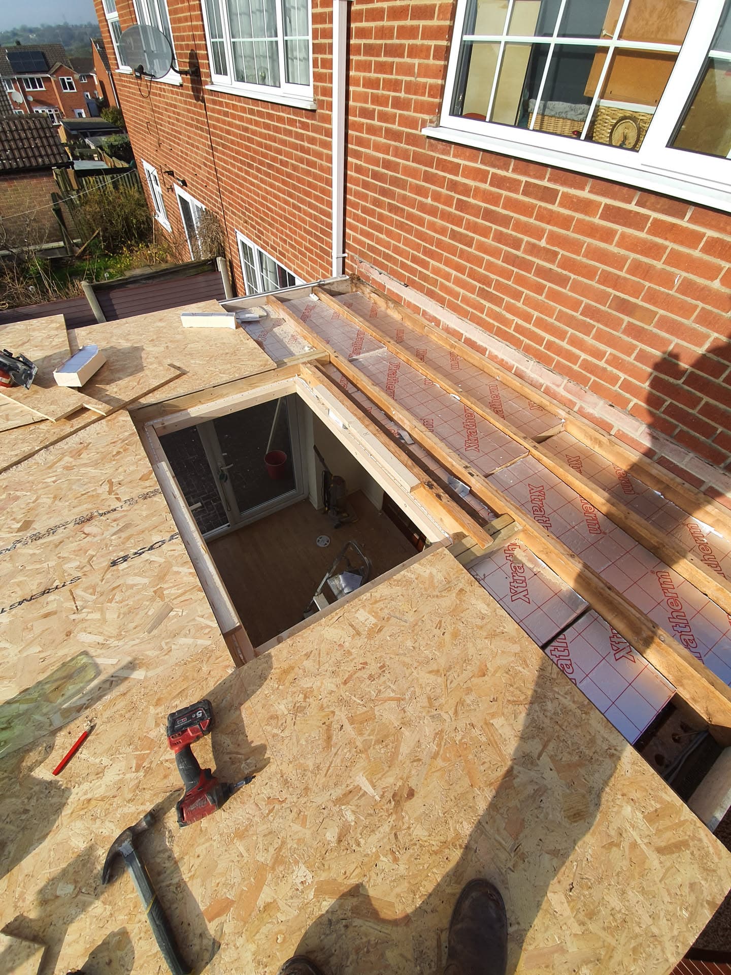 Flat roof construction in progress with OSB decking and breathable membrane around dormer opening