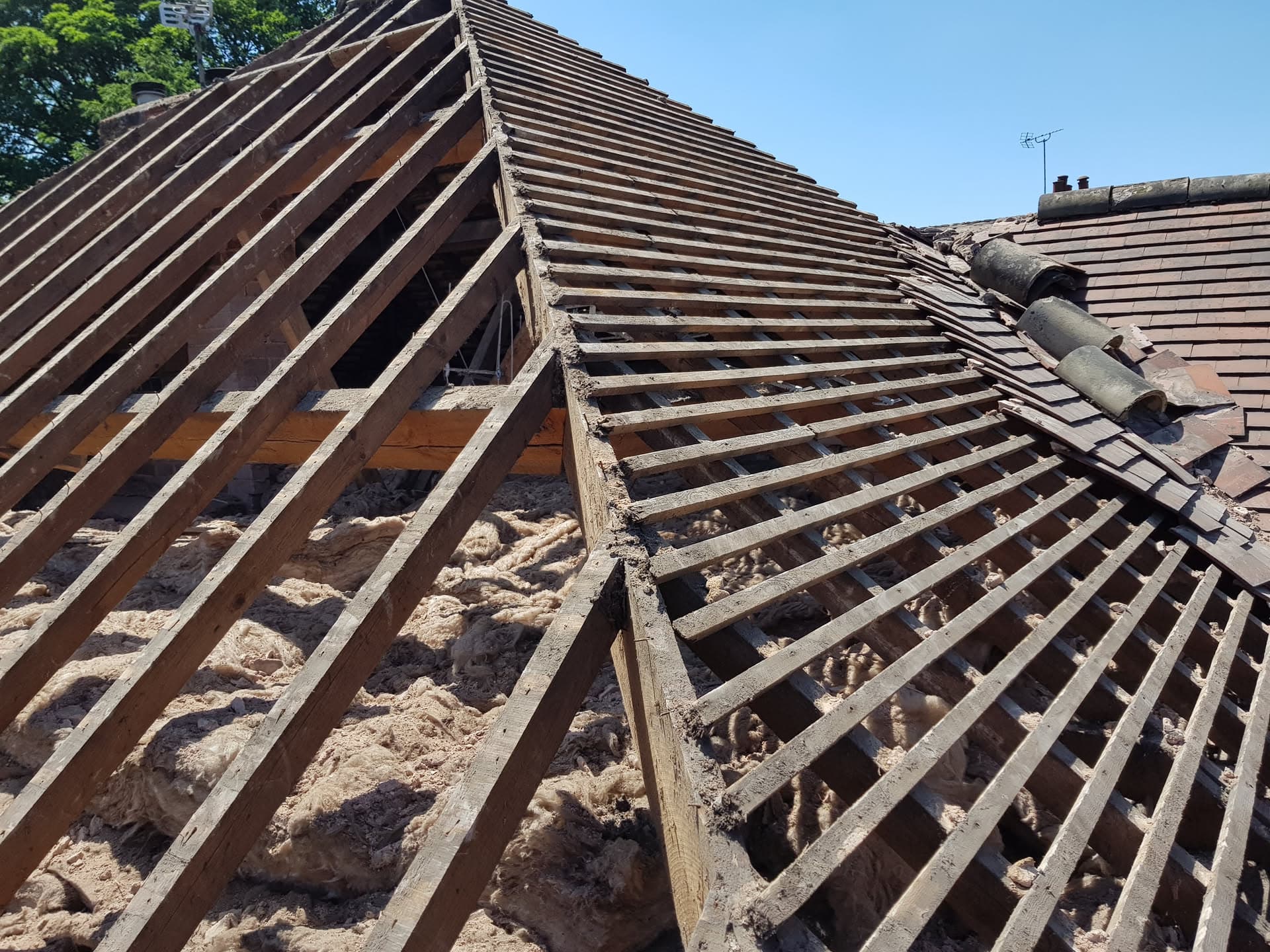 Pitched roof with exposed timber battens and insulation during tile replacement work