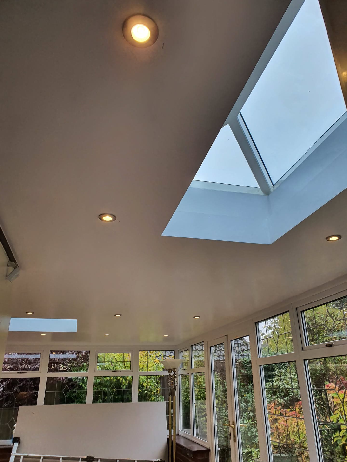 Interior view of conservatory with white ceiling, roof lanterns and recessed spotlights