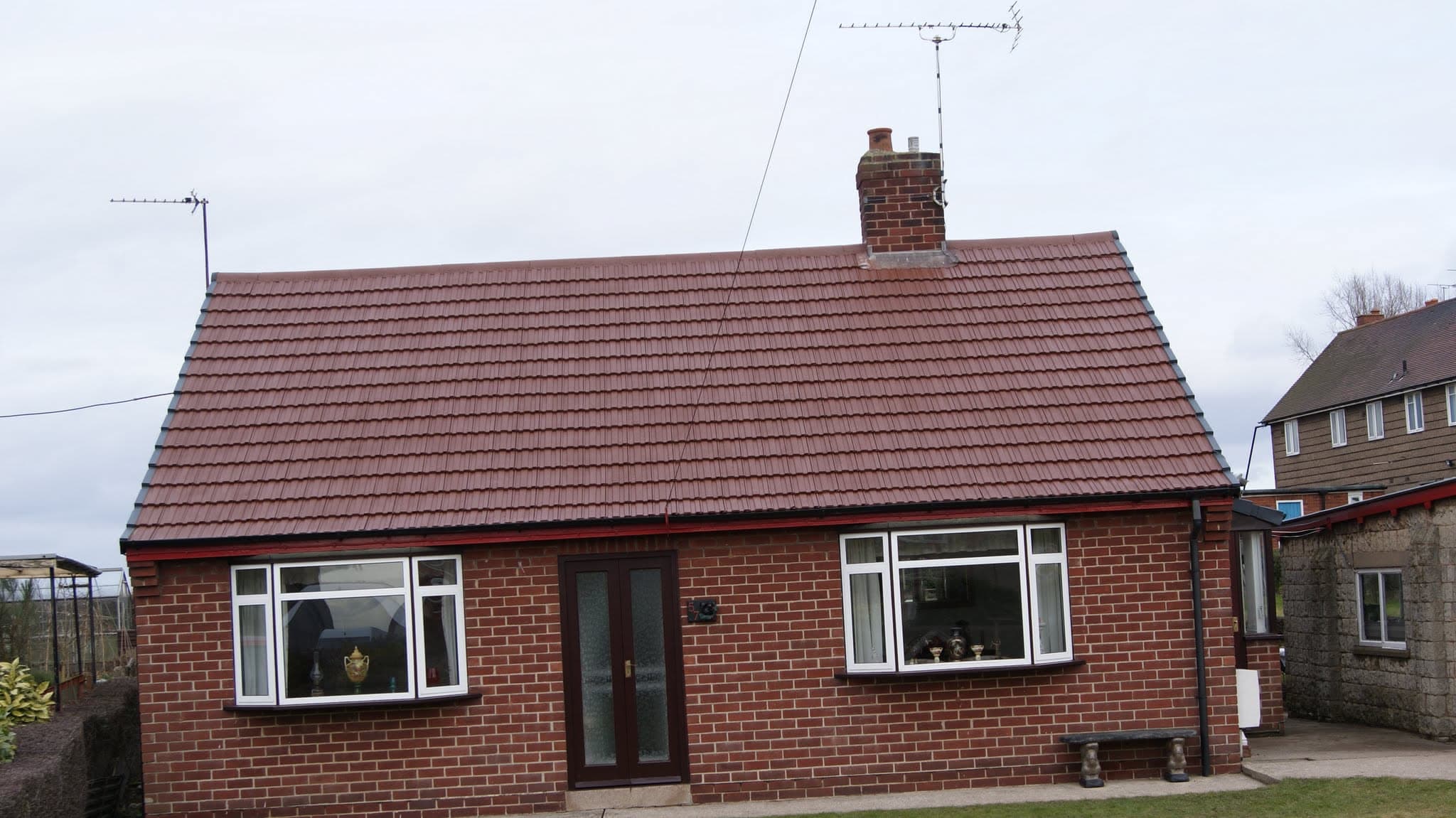 Red concrete tiled pitched roof on brick bungalow with chimney stack