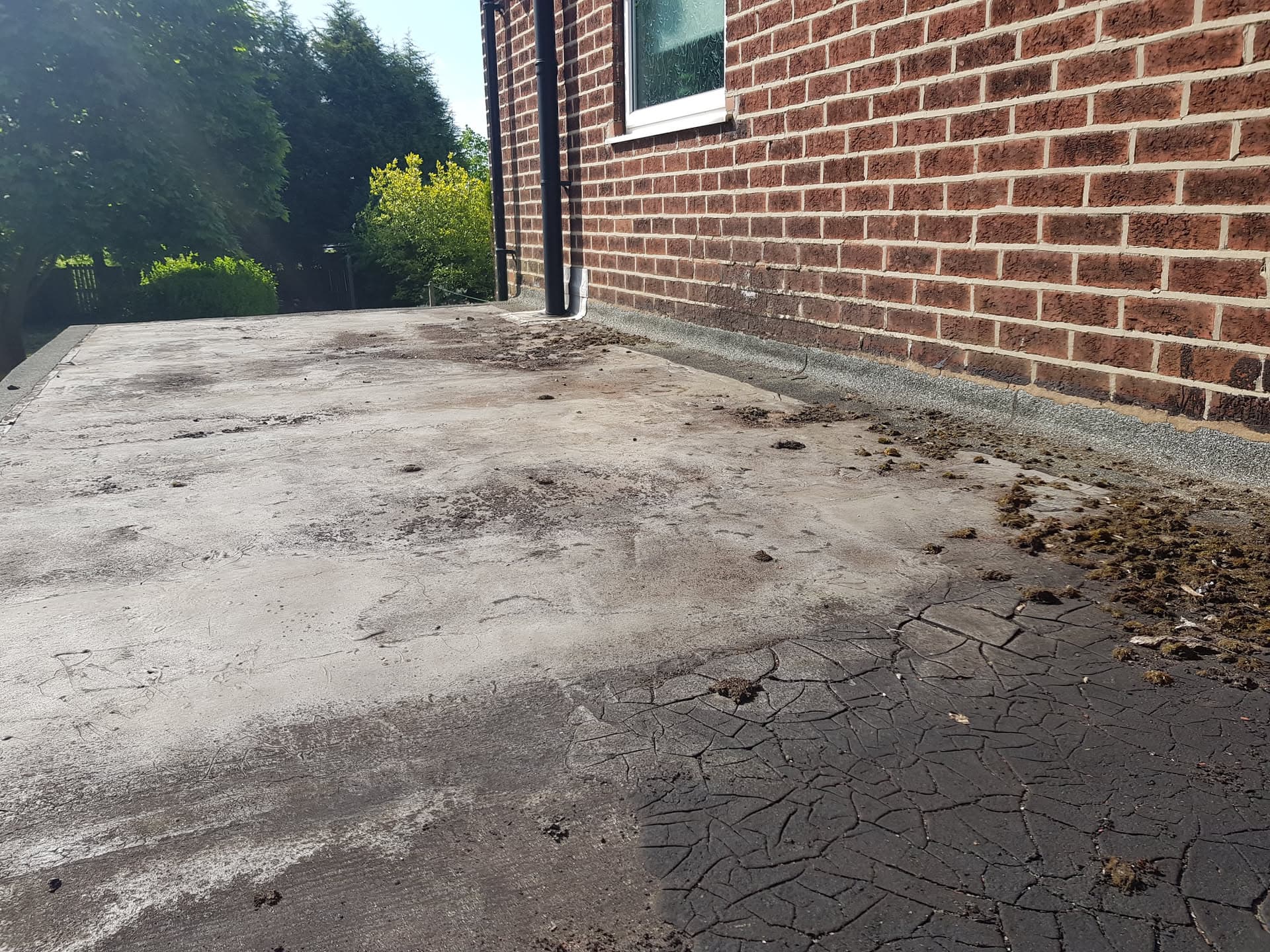Flat roof with cracked and deteriorating felt surface showing weathering and damage