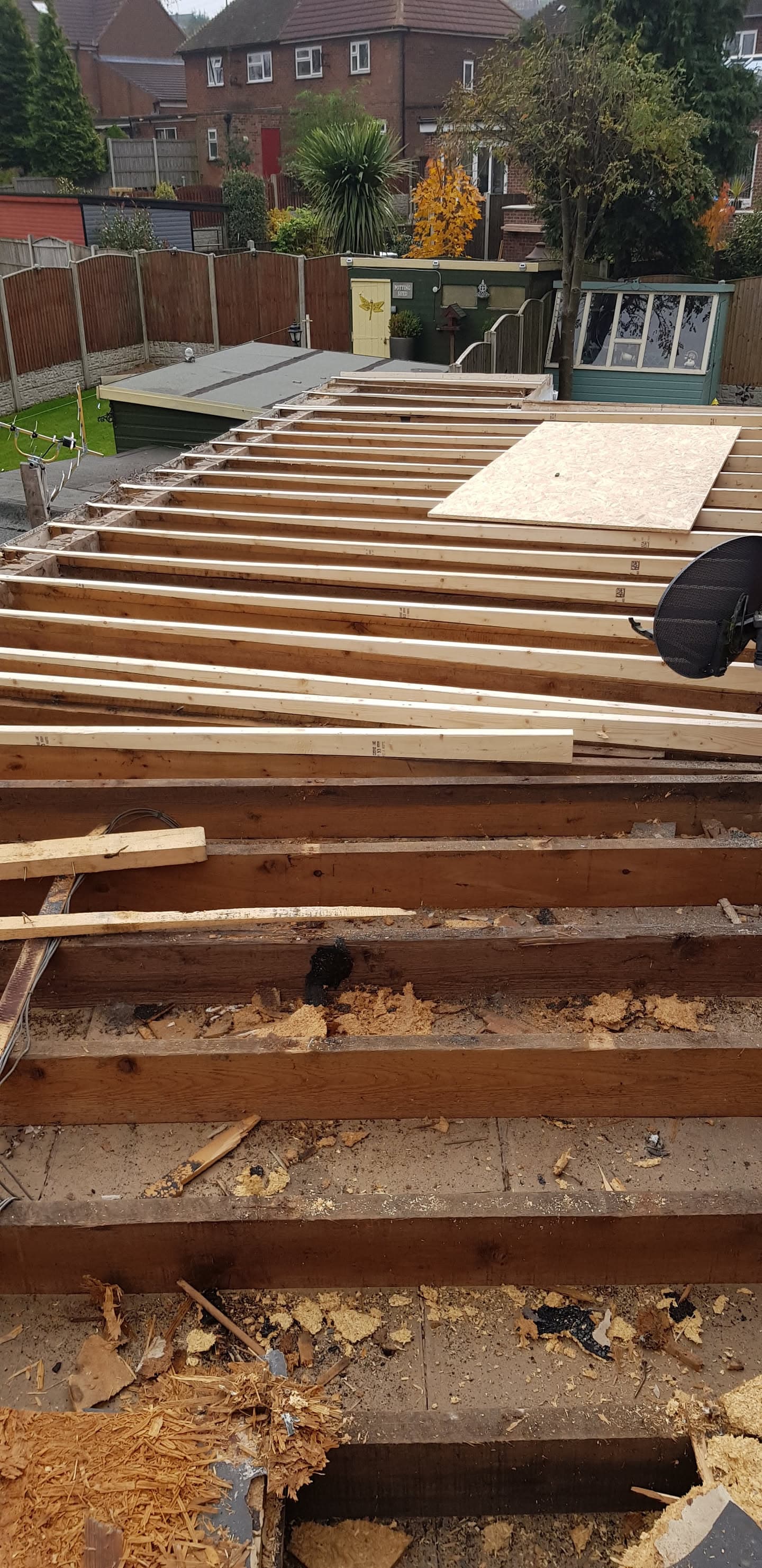 Timber joists being installed on flat roof structure with plywood decking partially laid