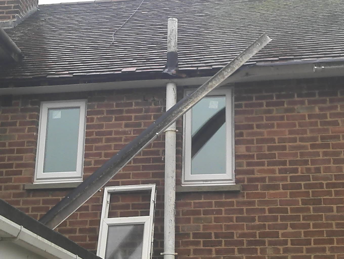 Pitched roof with dark grey concrete tiles, fascias and guttering on brick house