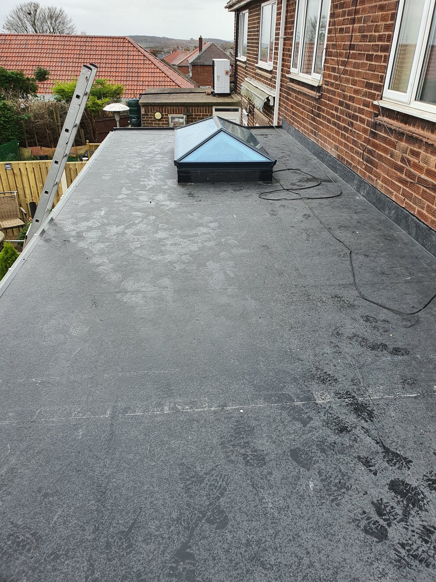 Flat roof with grey felt covering and central roof lantern on residential extension