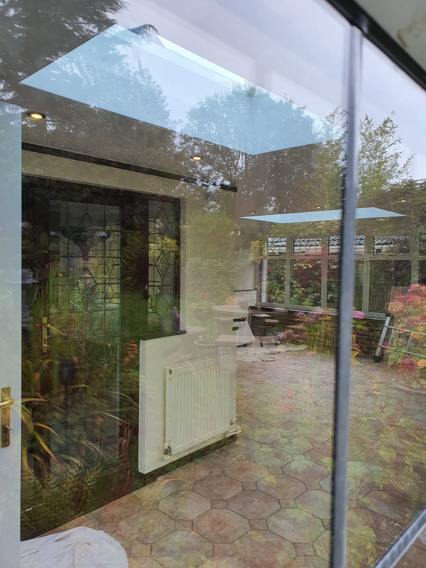 Conservatory with glass roof panels and white uPVC frame overlooking garden