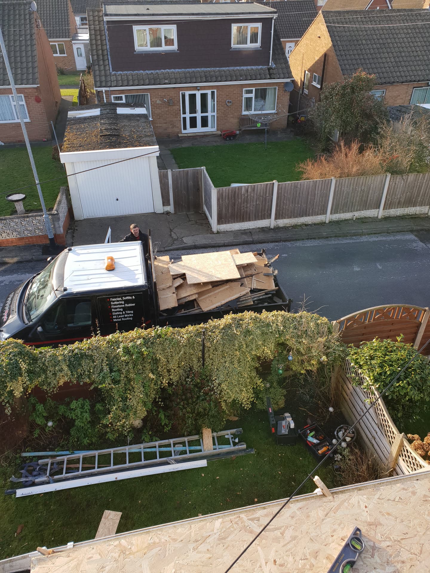 Flat roof installation in progress with OSB decking visible and materials loaded on van