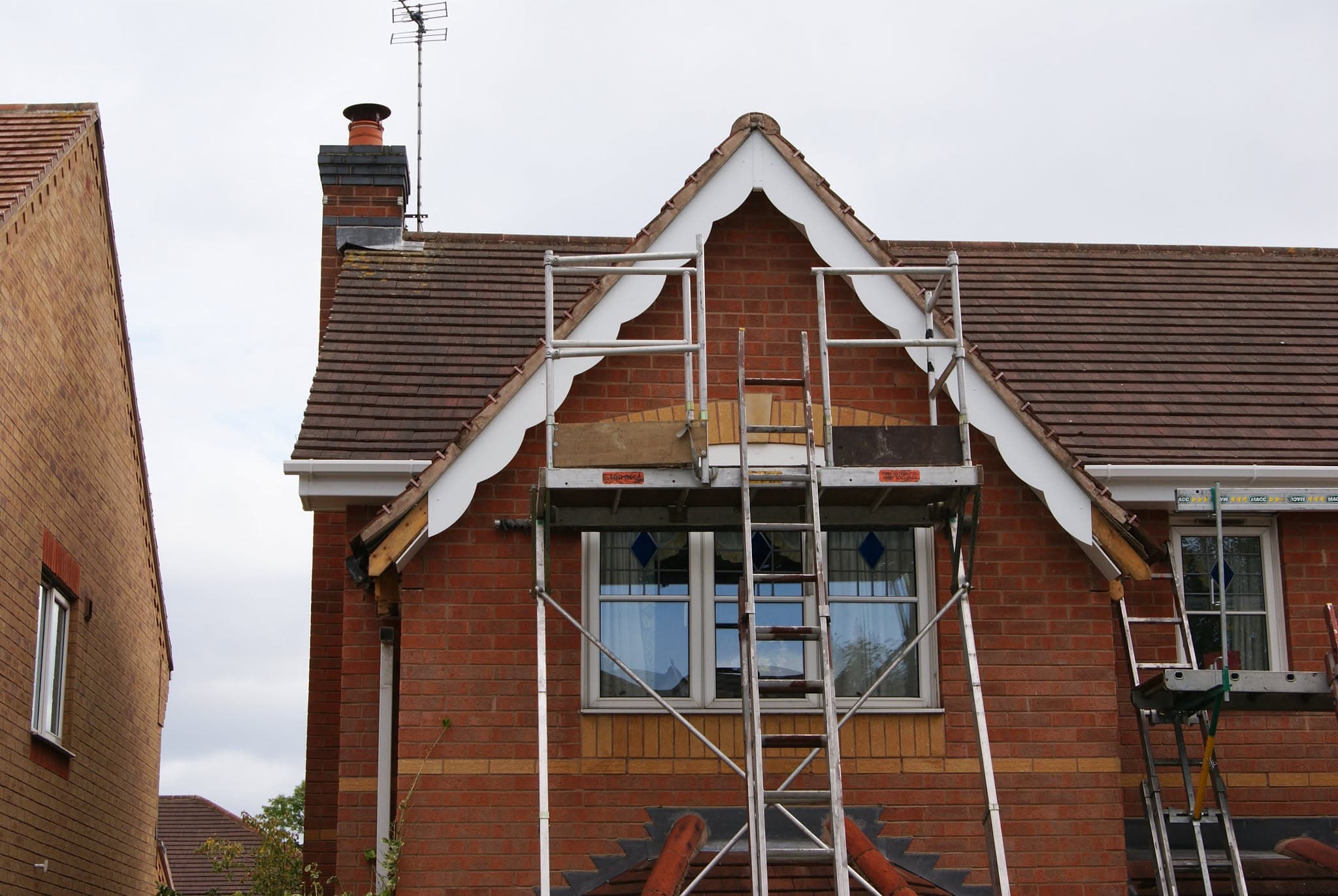 Pitched tiled roof with scaffolding tower positioned at gable end and chimney stack