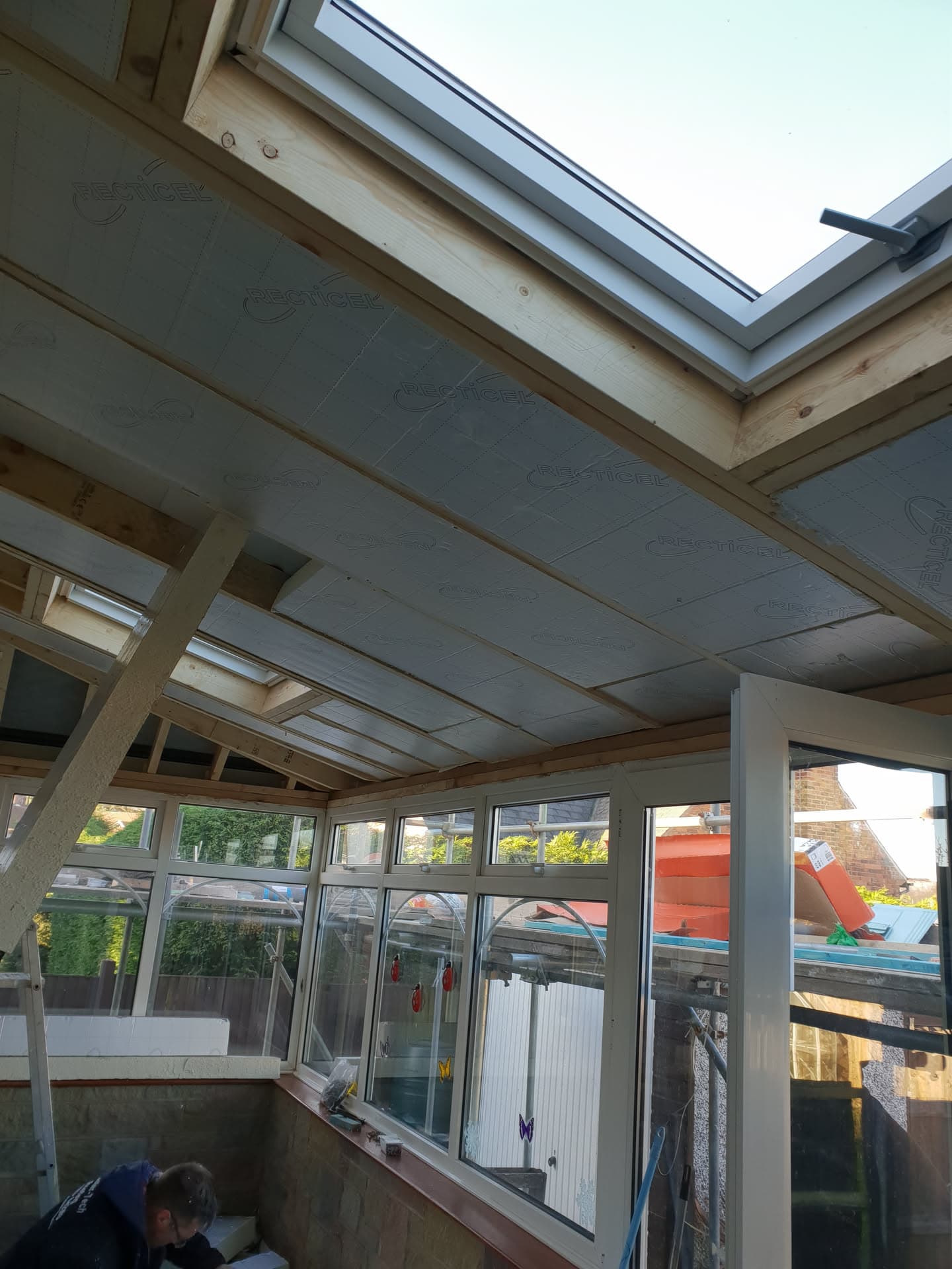 Interior view of conservatory roof installation with timber frame, insulation boards and roof window