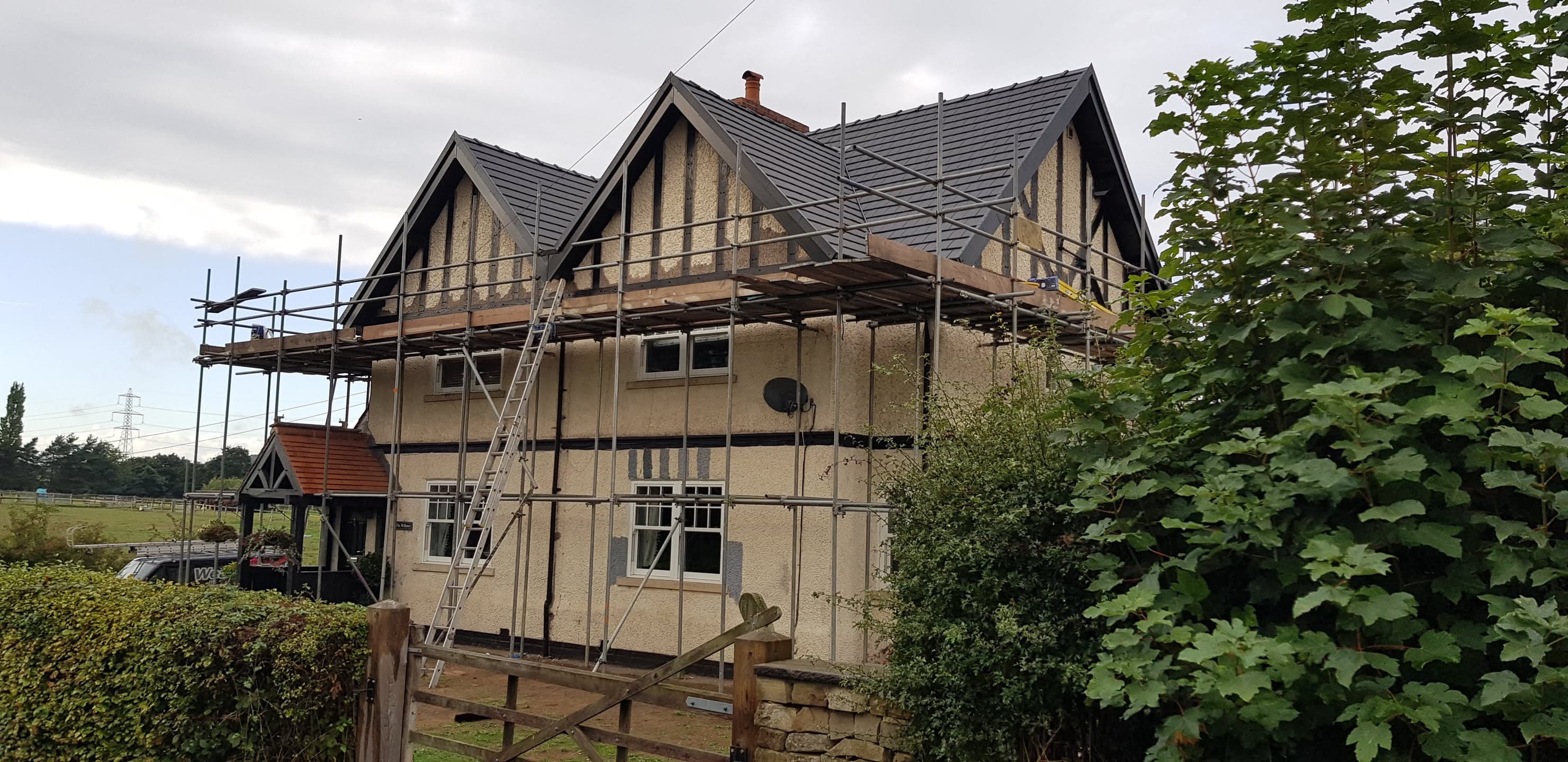 Pitched roof with grey concrete tiles and scaffolding around residential property