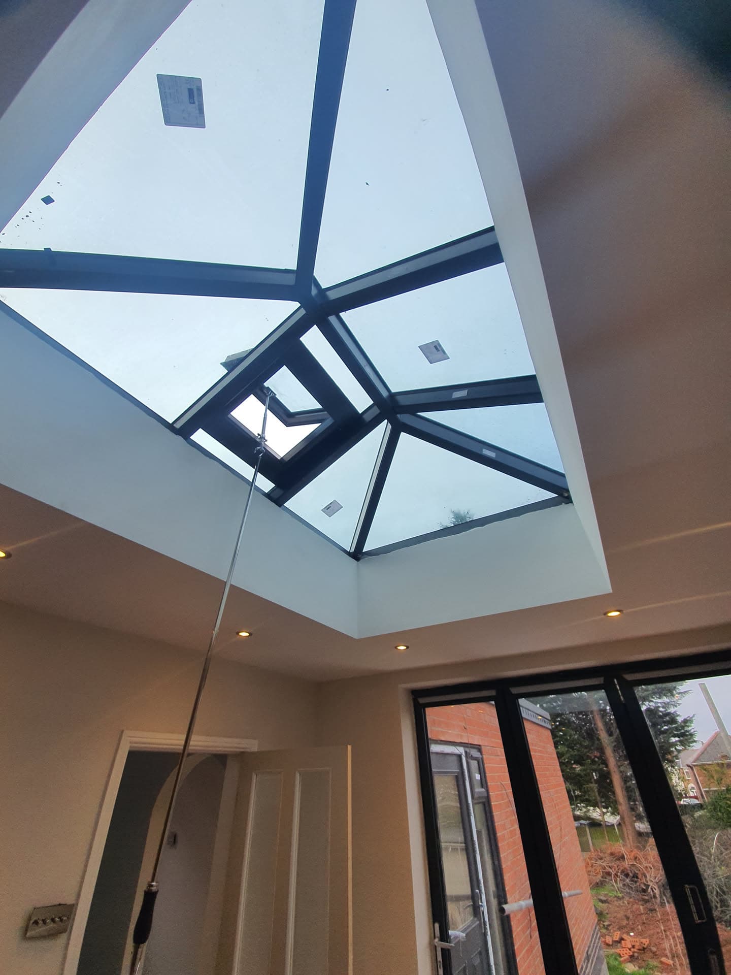 Interior view of completed conservatory roof with dark grey aluminium framework and glass panels