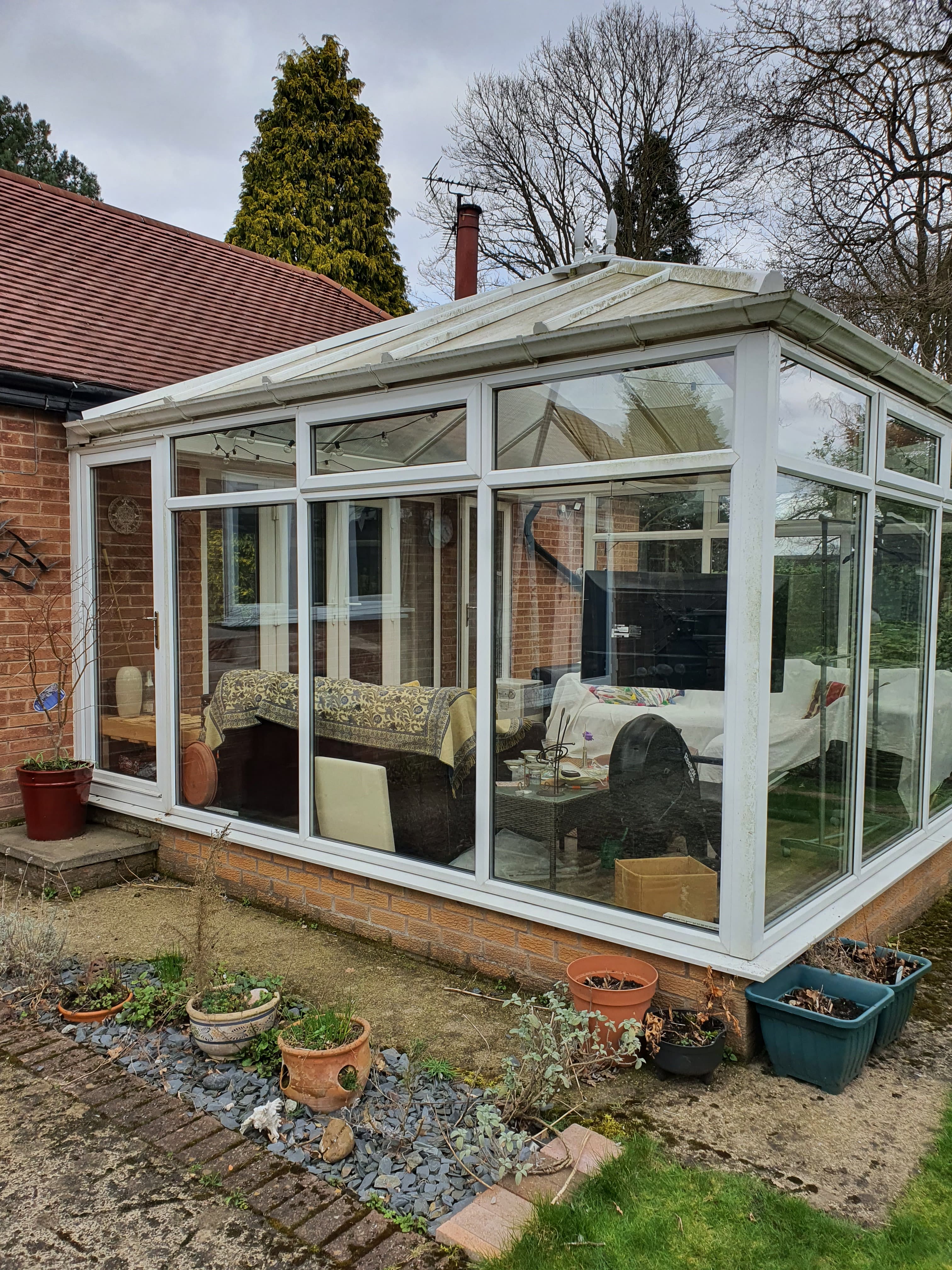 White uPVC conservatory with glazed roof attached to brick house with red tiled roof