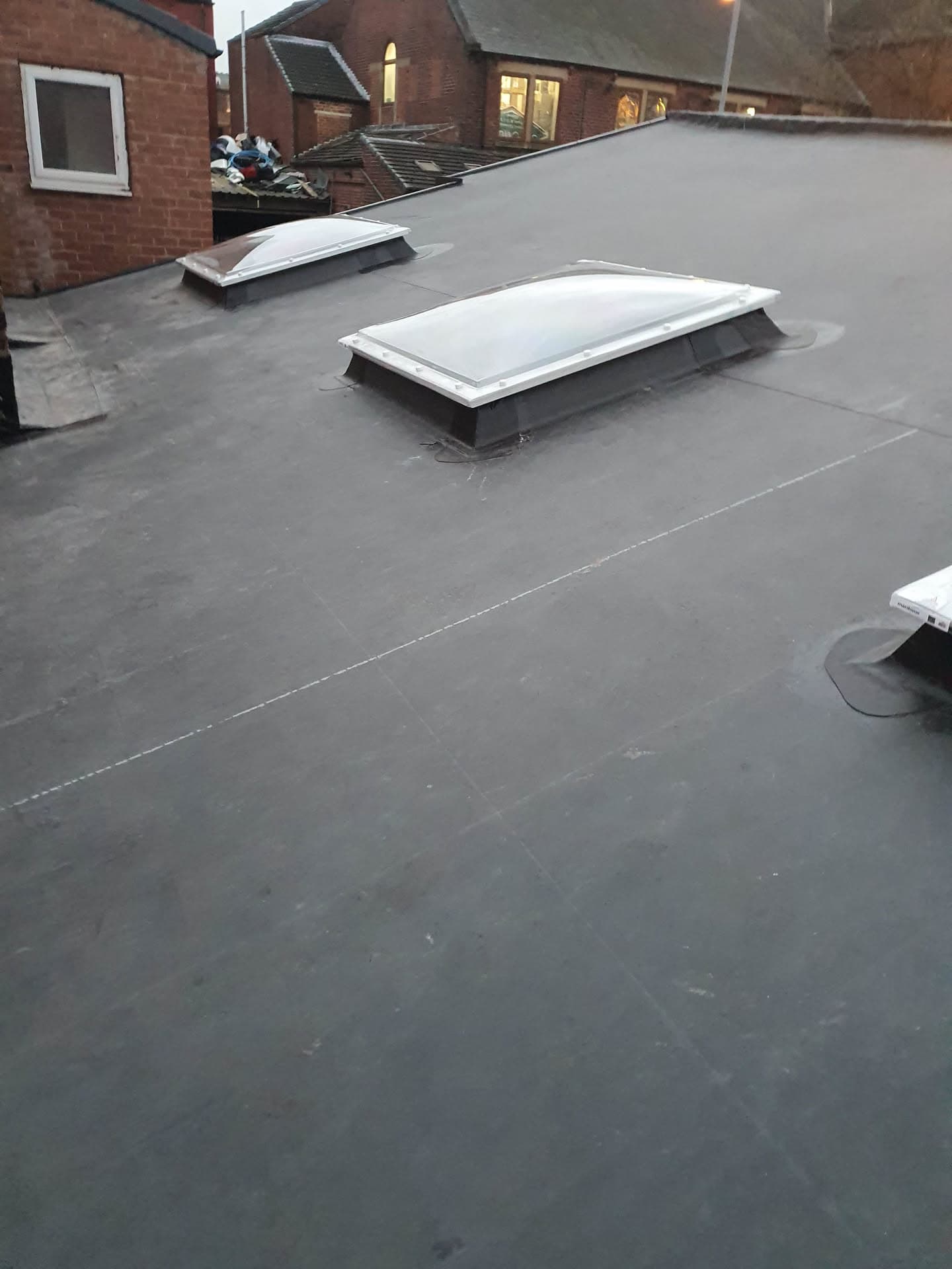 Grey flat roof with two white-framed skylights on residential property