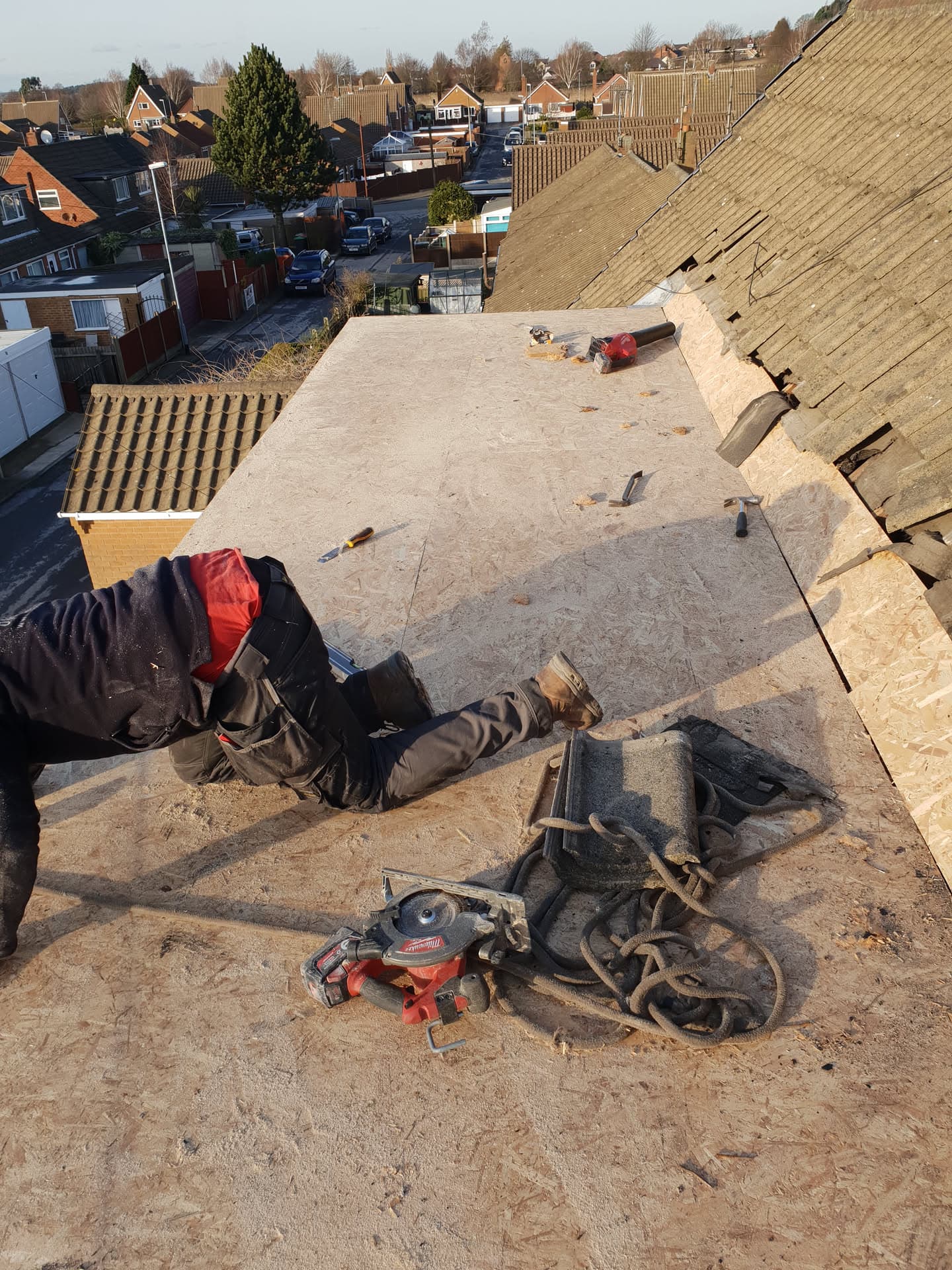 Fitters installing felt flat roof with tools and materials on residential property