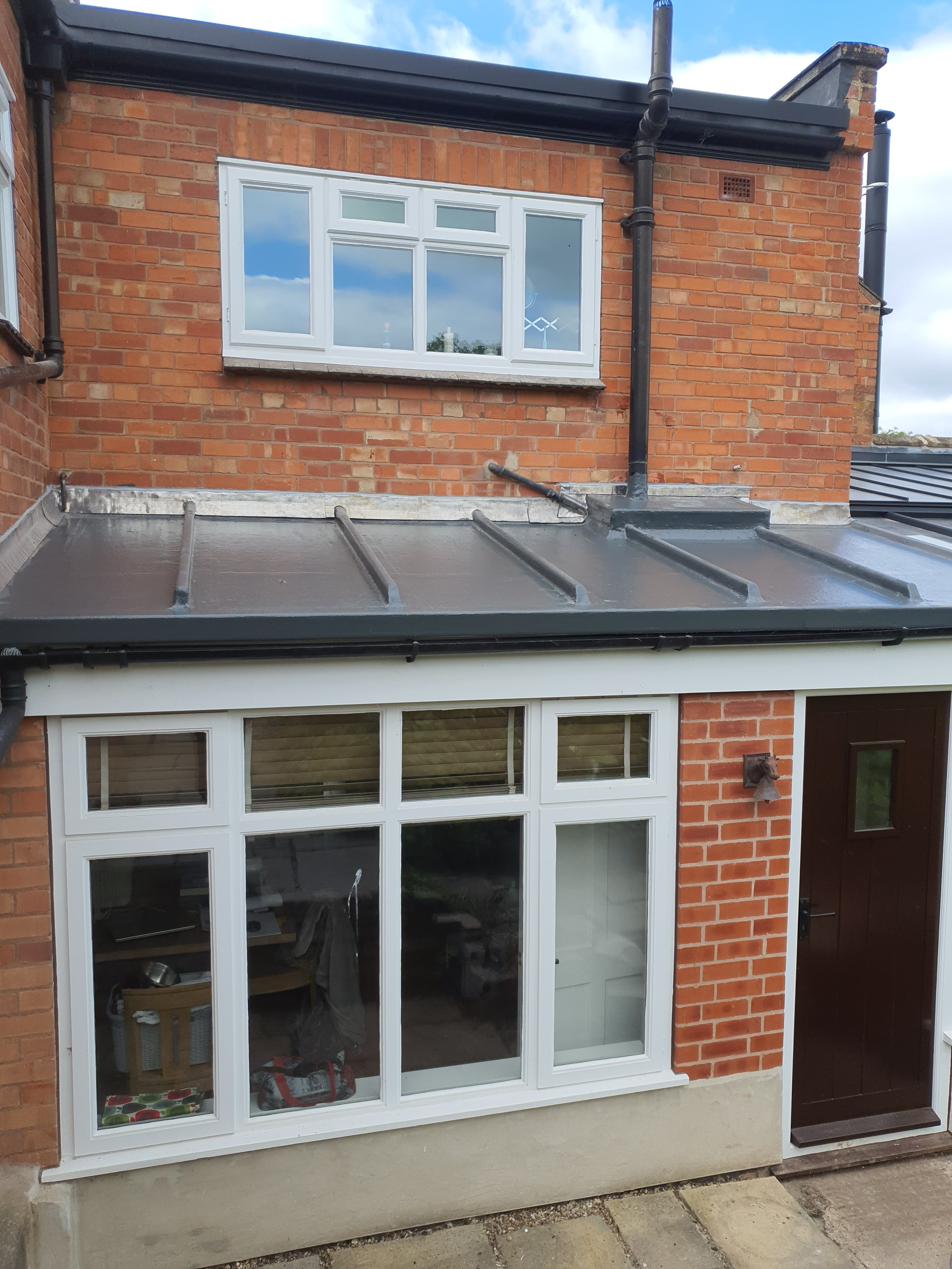Anthracite standing seam metal roof on single-storey extension with white fascia and guttering