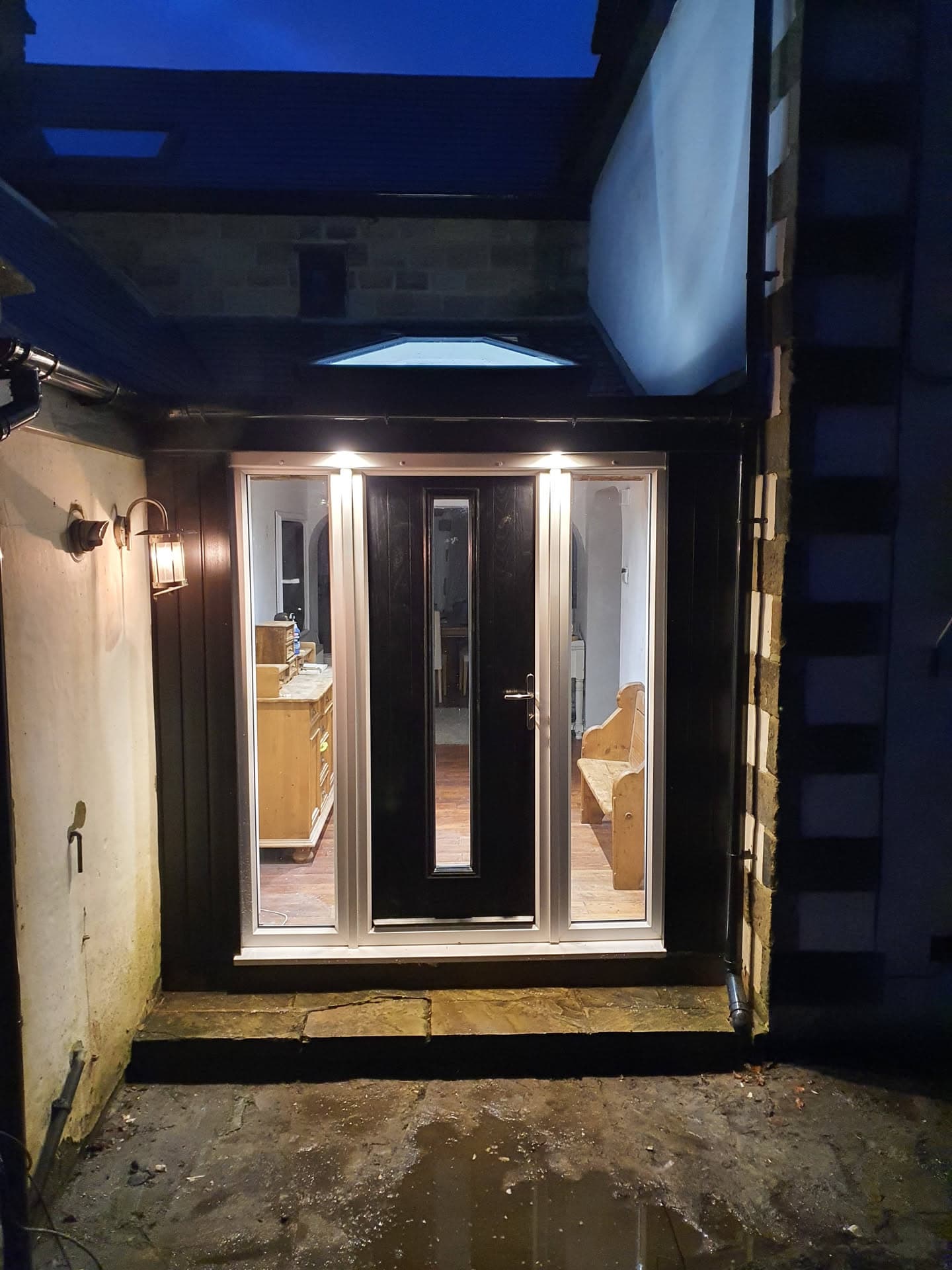 Flat roof installation with dark membrane above residential entrance at night