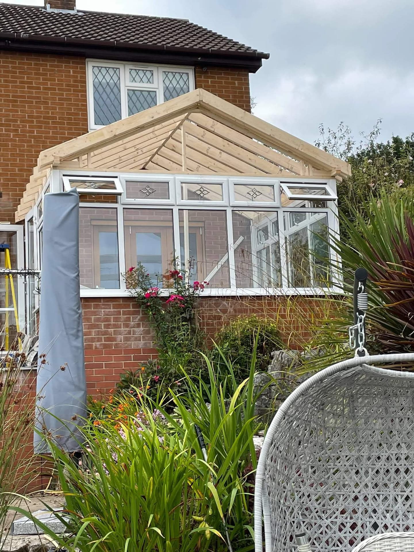 New timber conservatory roof frame under construction with white uPVC windows