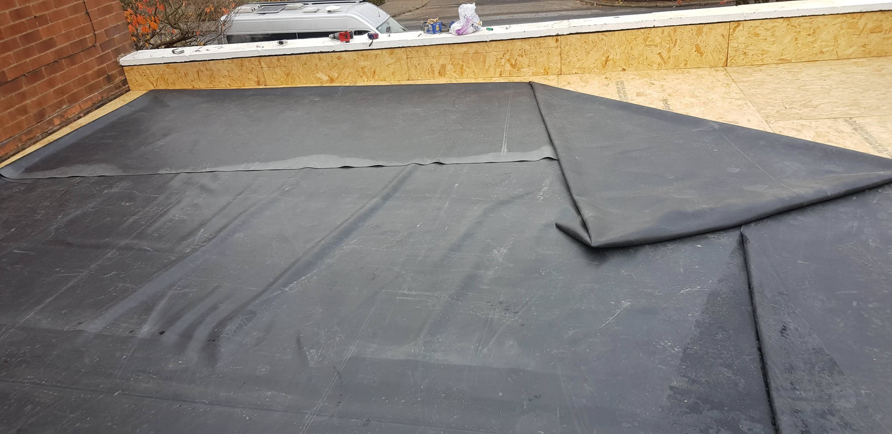 Flat roof with grey EPDM rubber membrane and timber parapet wall