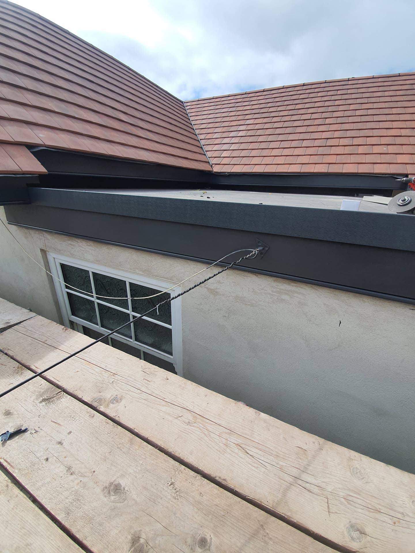 Pitched roof with brown concrete tiles and anthracite fascias and guttering