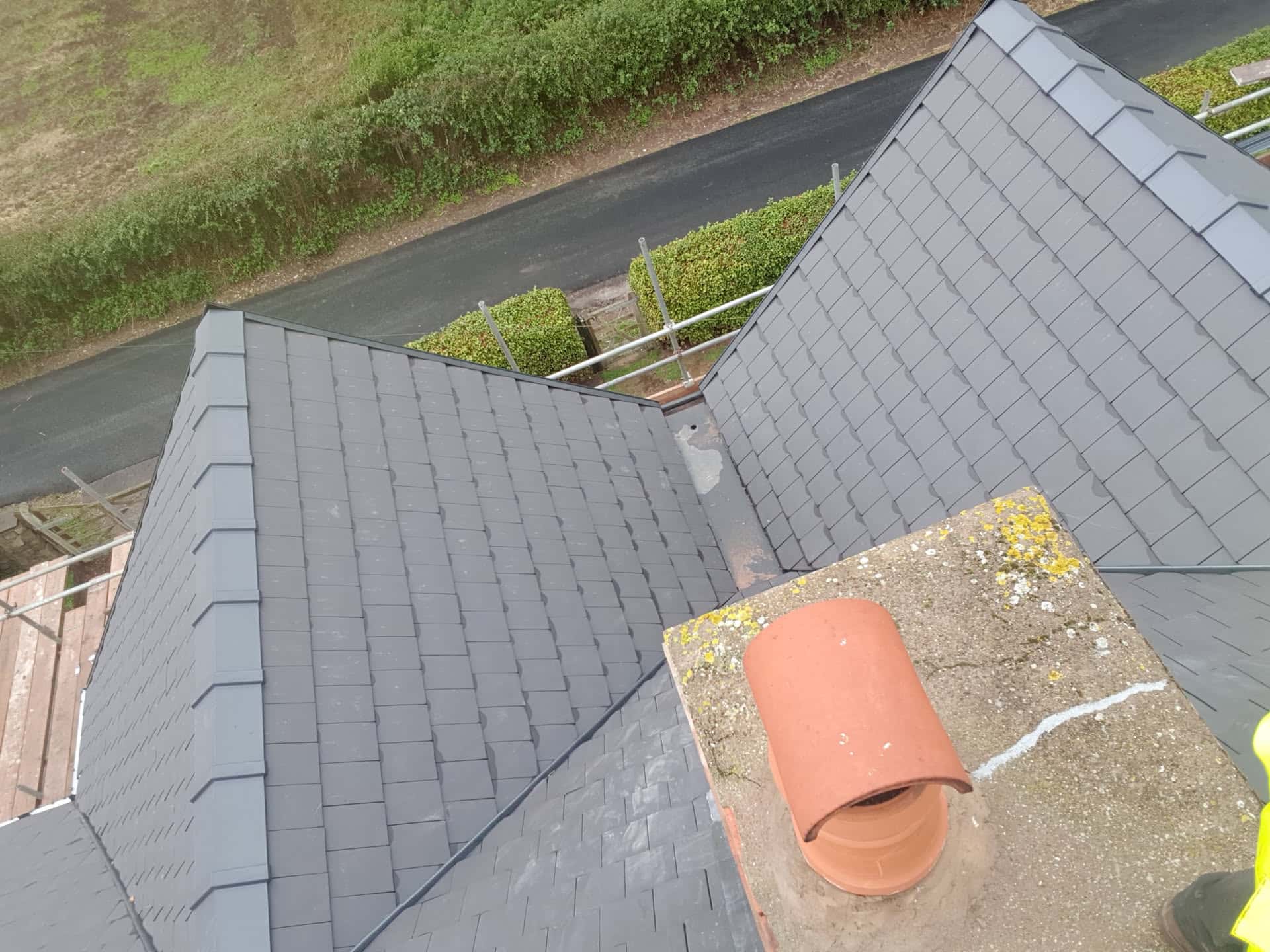 Aerial view of completed pitched roof with grey slate tiles and terracotta chimney pot