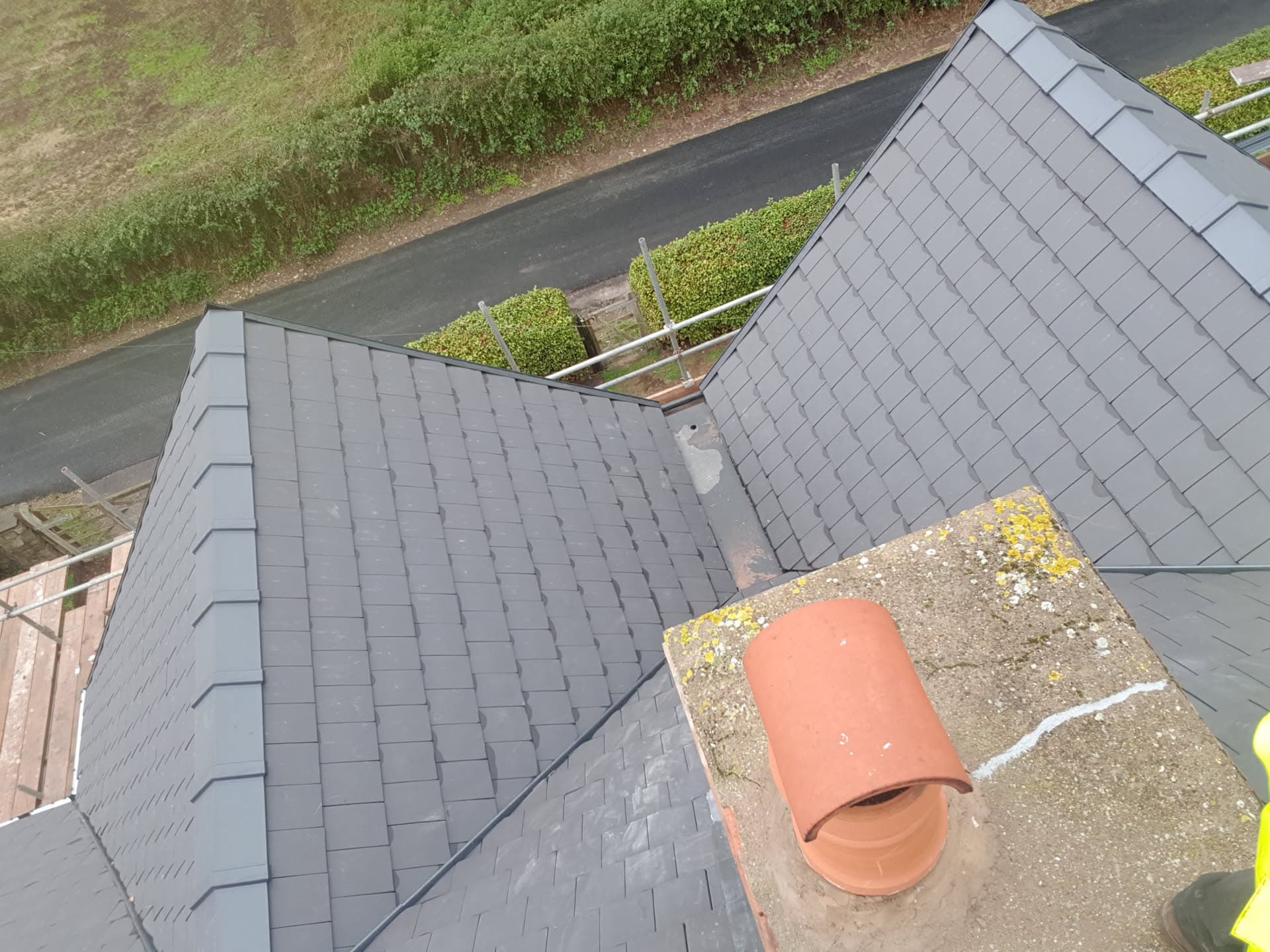 Aerial view of completed pitched roof with grey slate tiles and terracotta chimney pot