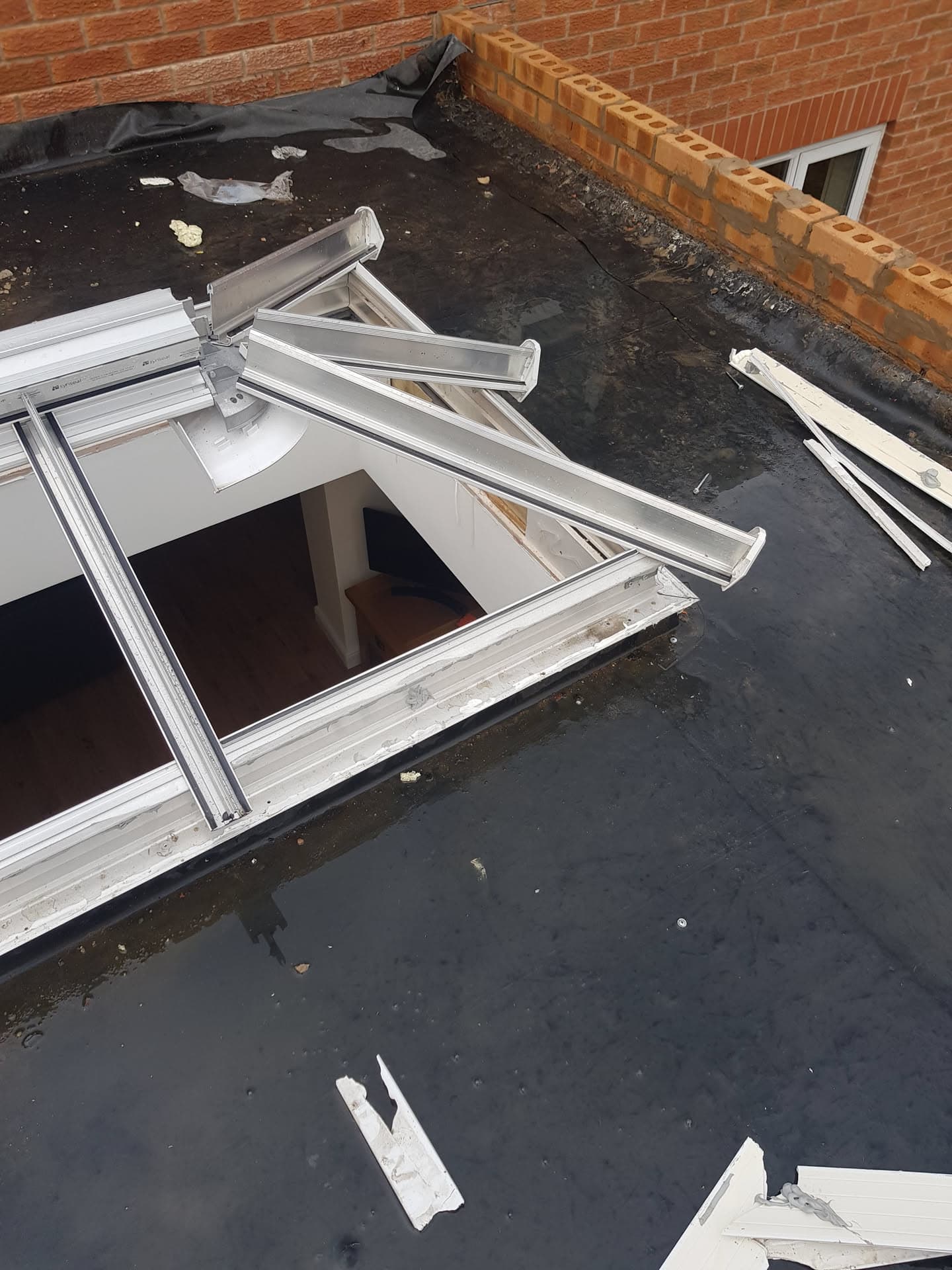 Flat roof with felt covering and white-framed roof lantern during installation