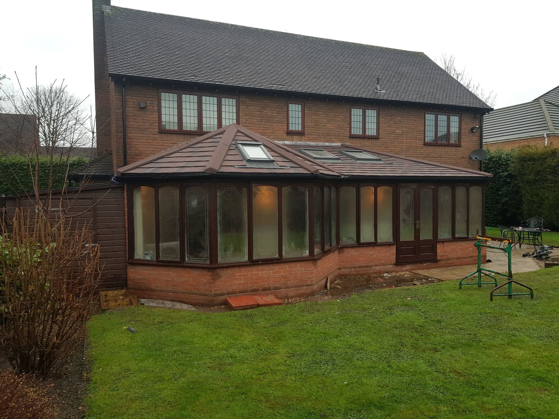 Brown conservatory with tiled pitched roof and roof windows on brick-built house