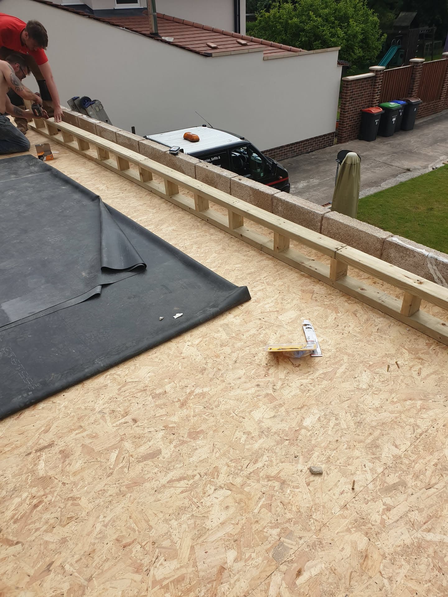 Fitter installing timber framework and felt membrane on flat roof