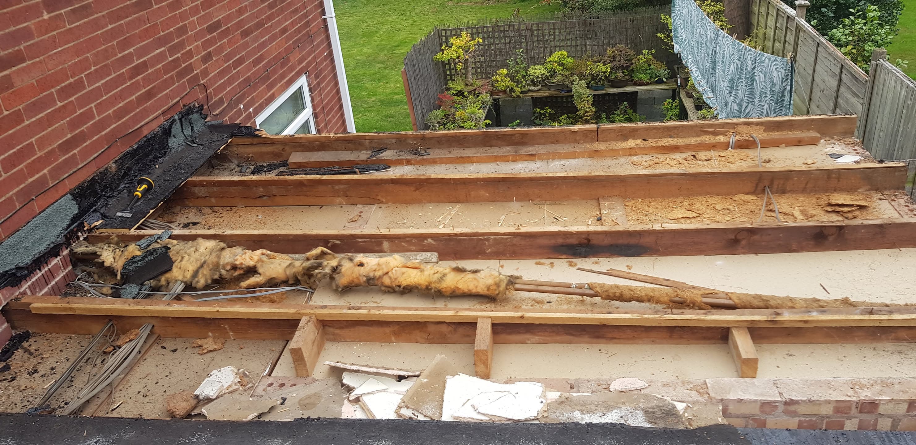 Flat roof stripped back to timber joists showing old insulation and decking removed during renovation