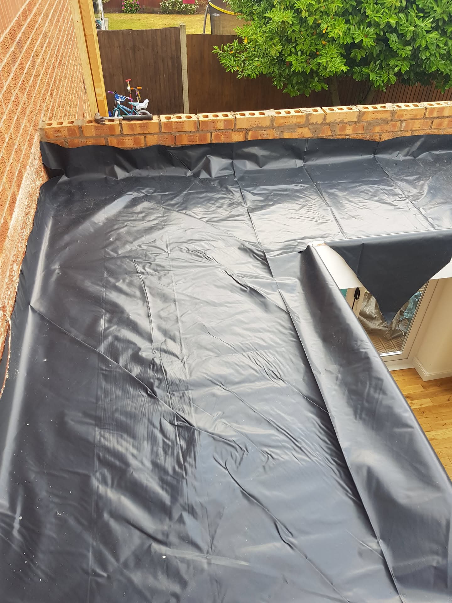 Flat roof with black EPDM rubber membrane installation and brick parapet wall