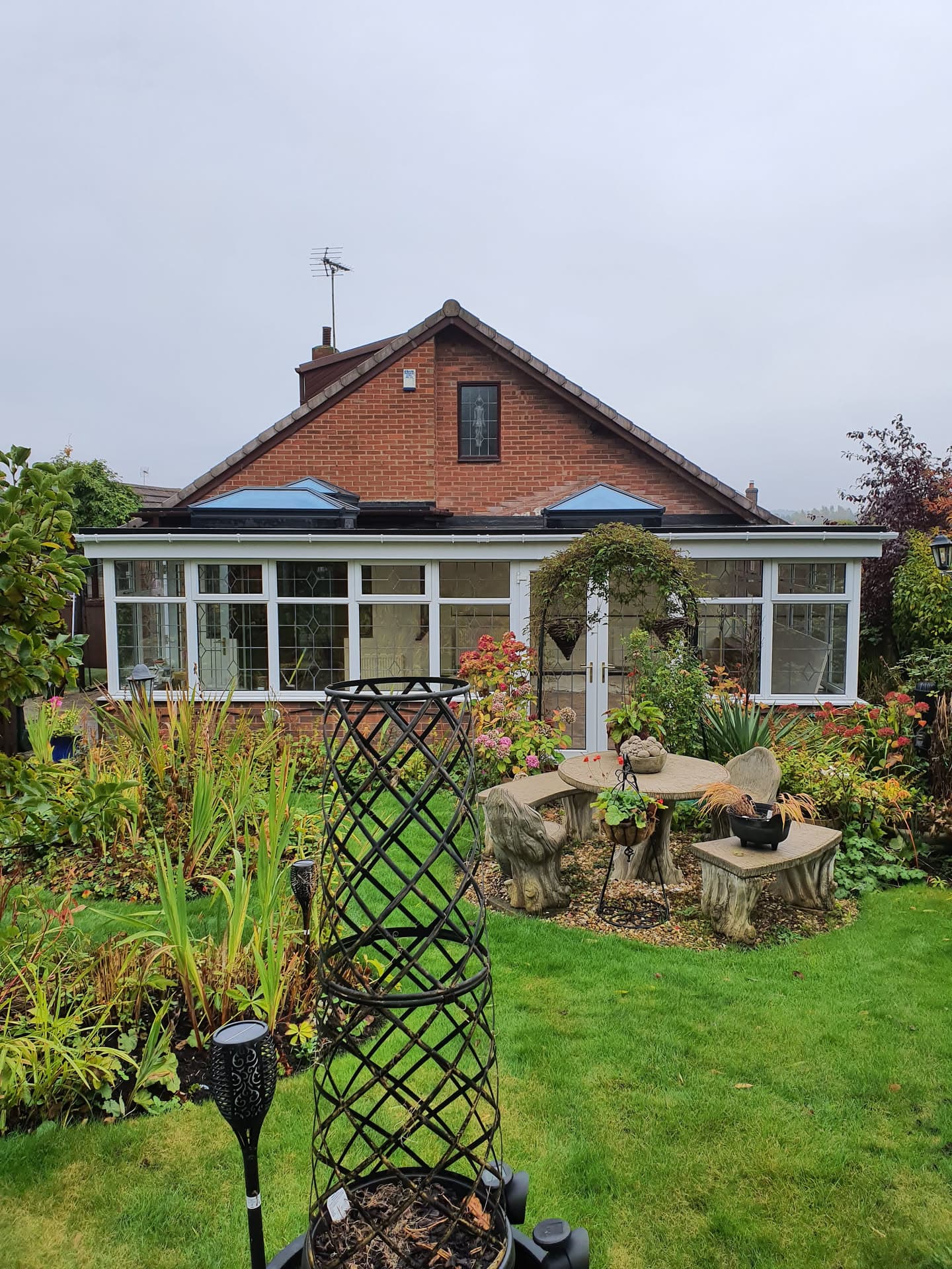 Conservatory with dark flat roof and white uPVC frames attached to brick house