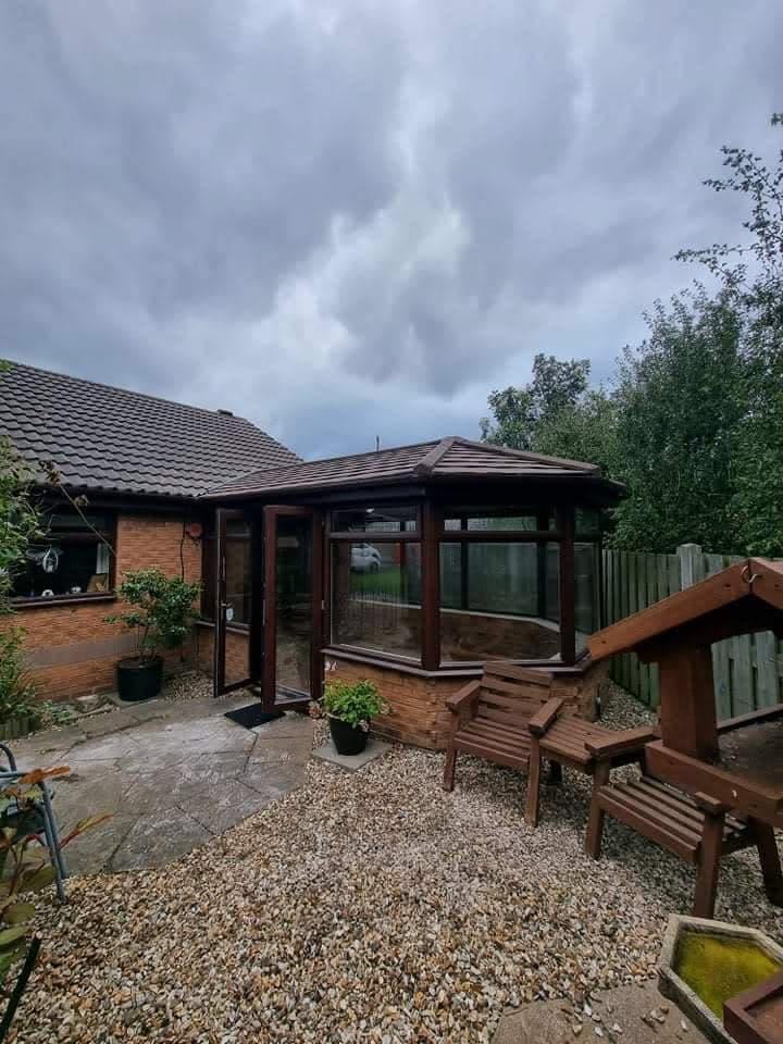 Conservatory with tiled roof and brown uPVC frames attached to brick bungalow