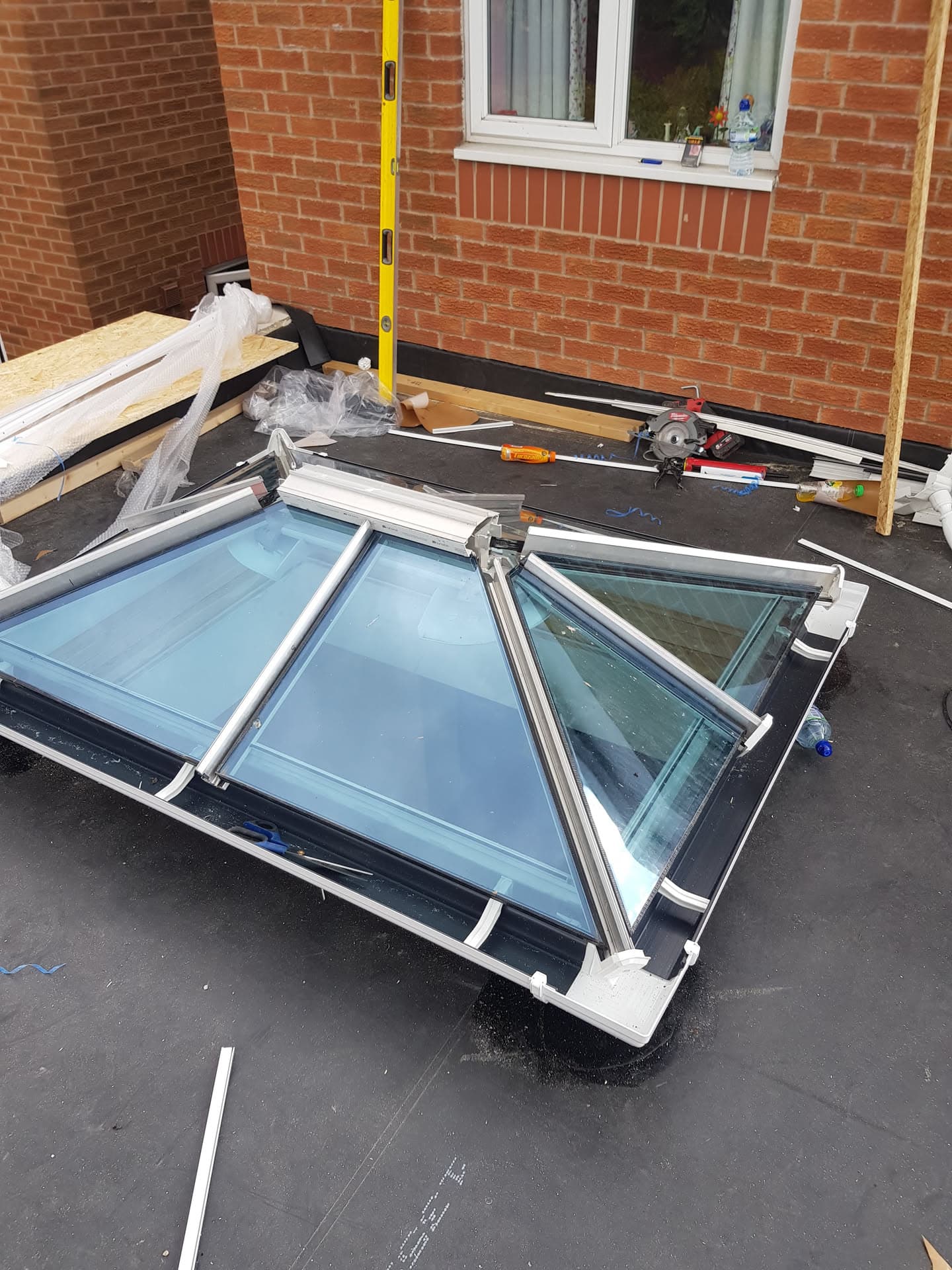Glass roof lanterns with white frames positioned on flat roof with tools and materials