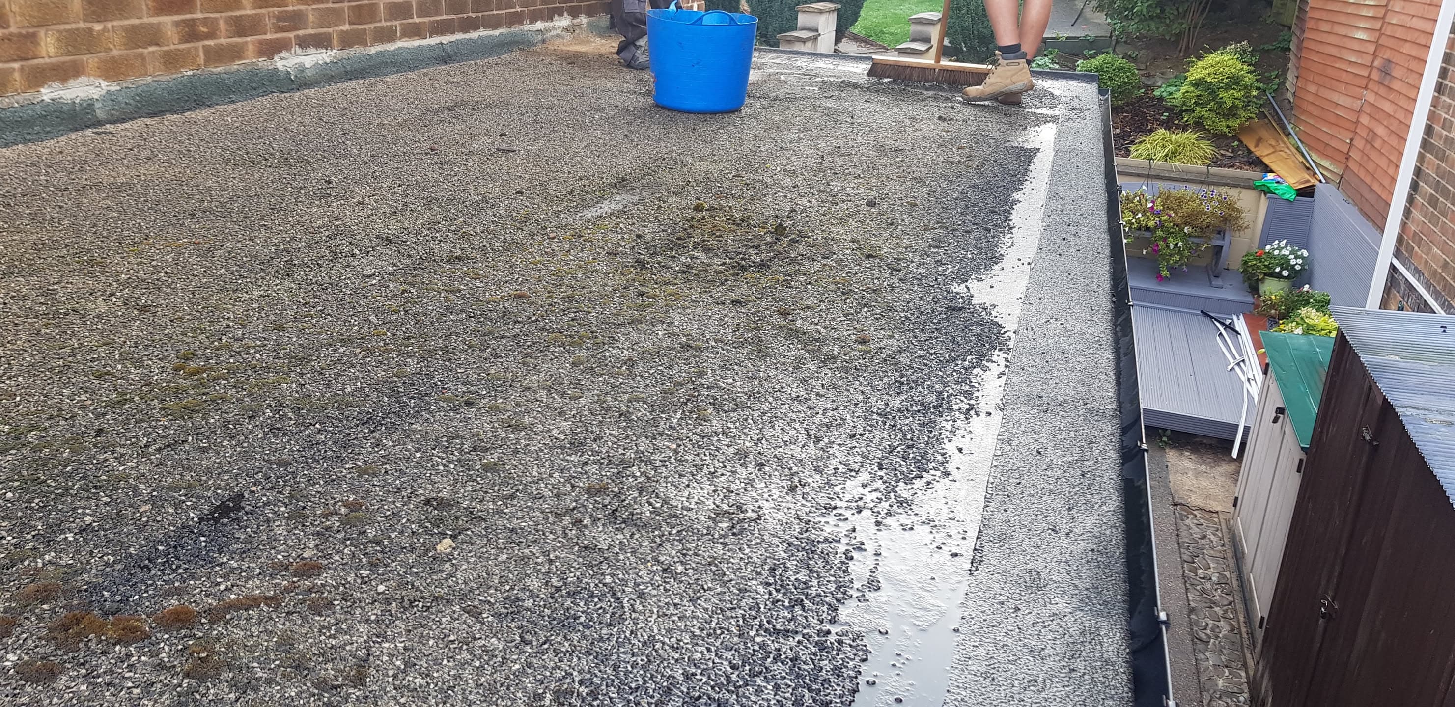 Flat roof with grey mineral felt surface and white edging trim