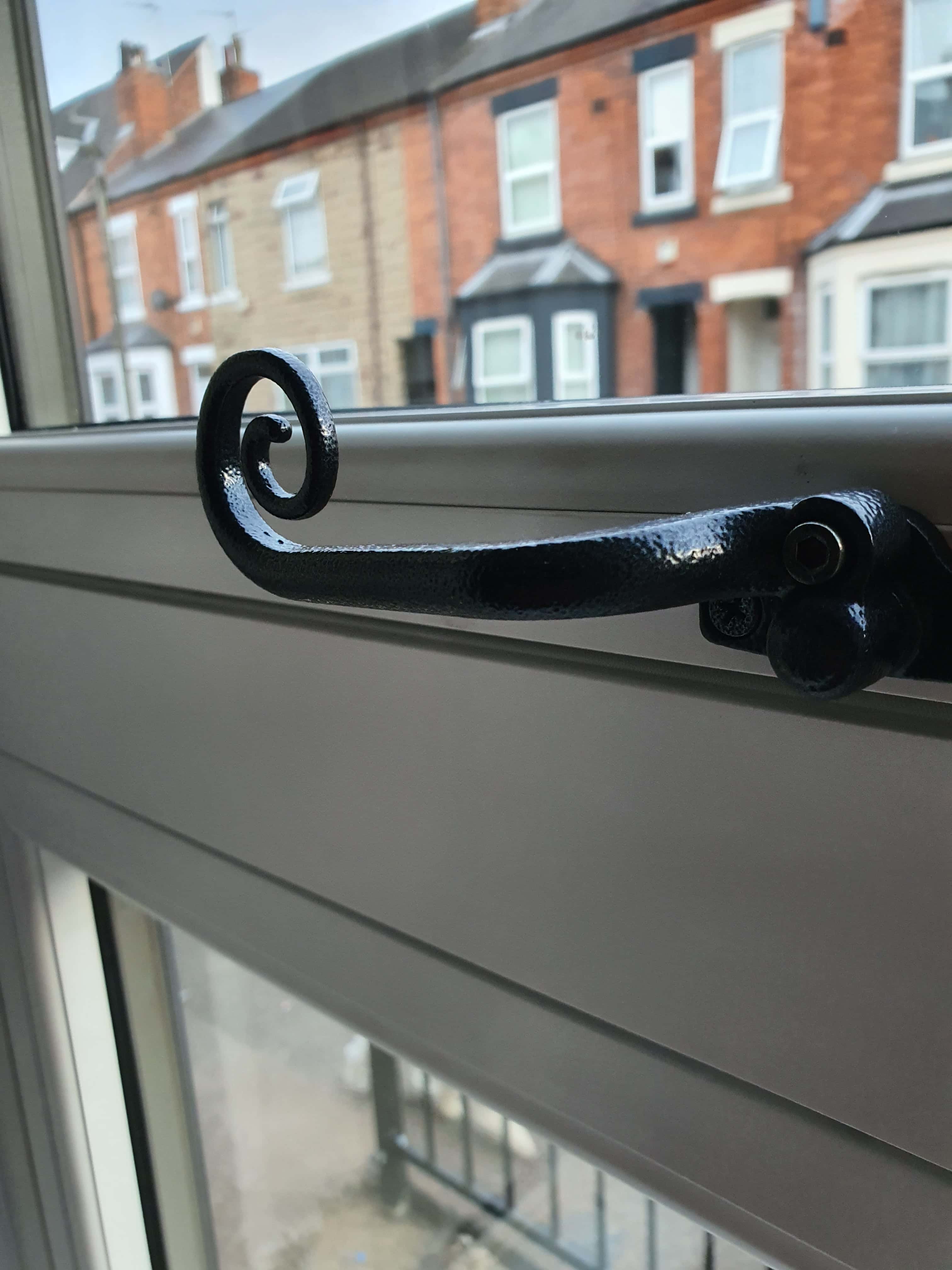 Black decorative window stay on grey painted timber window frame