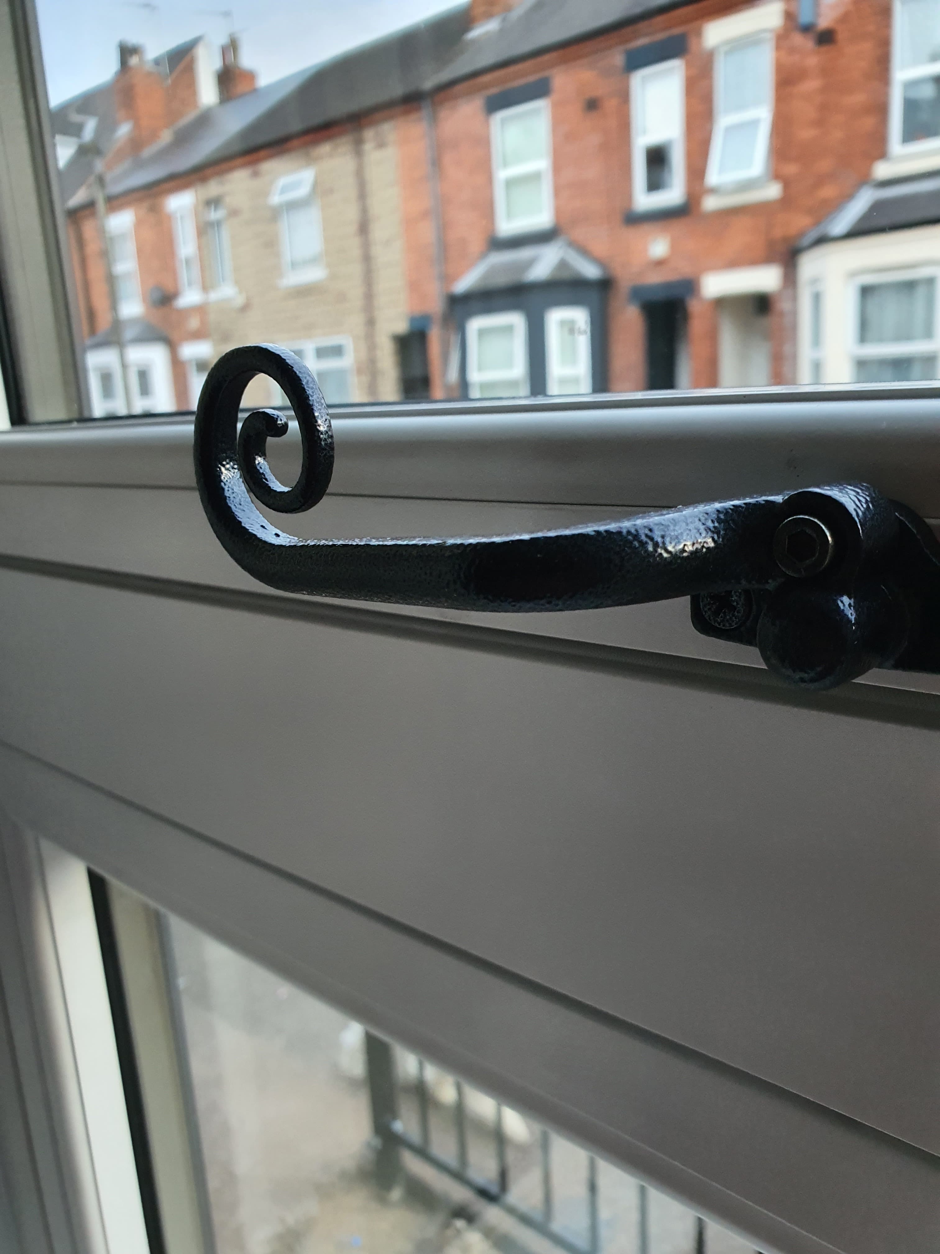 Black decorative window stay on grey painted timber window frame