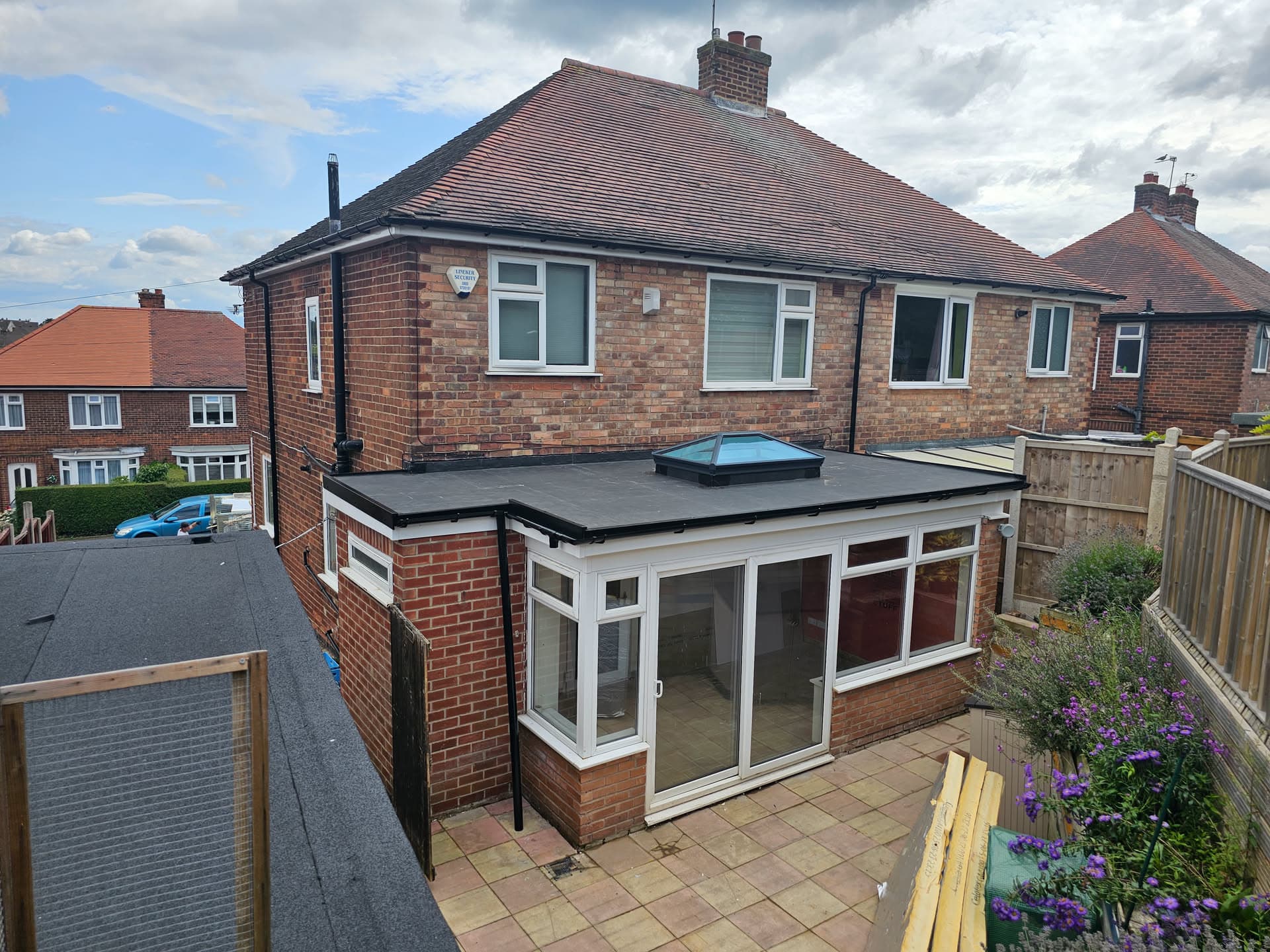 Flat roof extension with dark felt covering and lantern skylight on brick semi-detached house