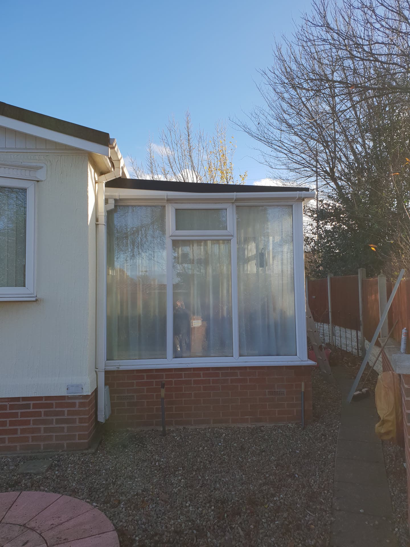 Flat roof installation on white uPVC conservatory extension with brick base