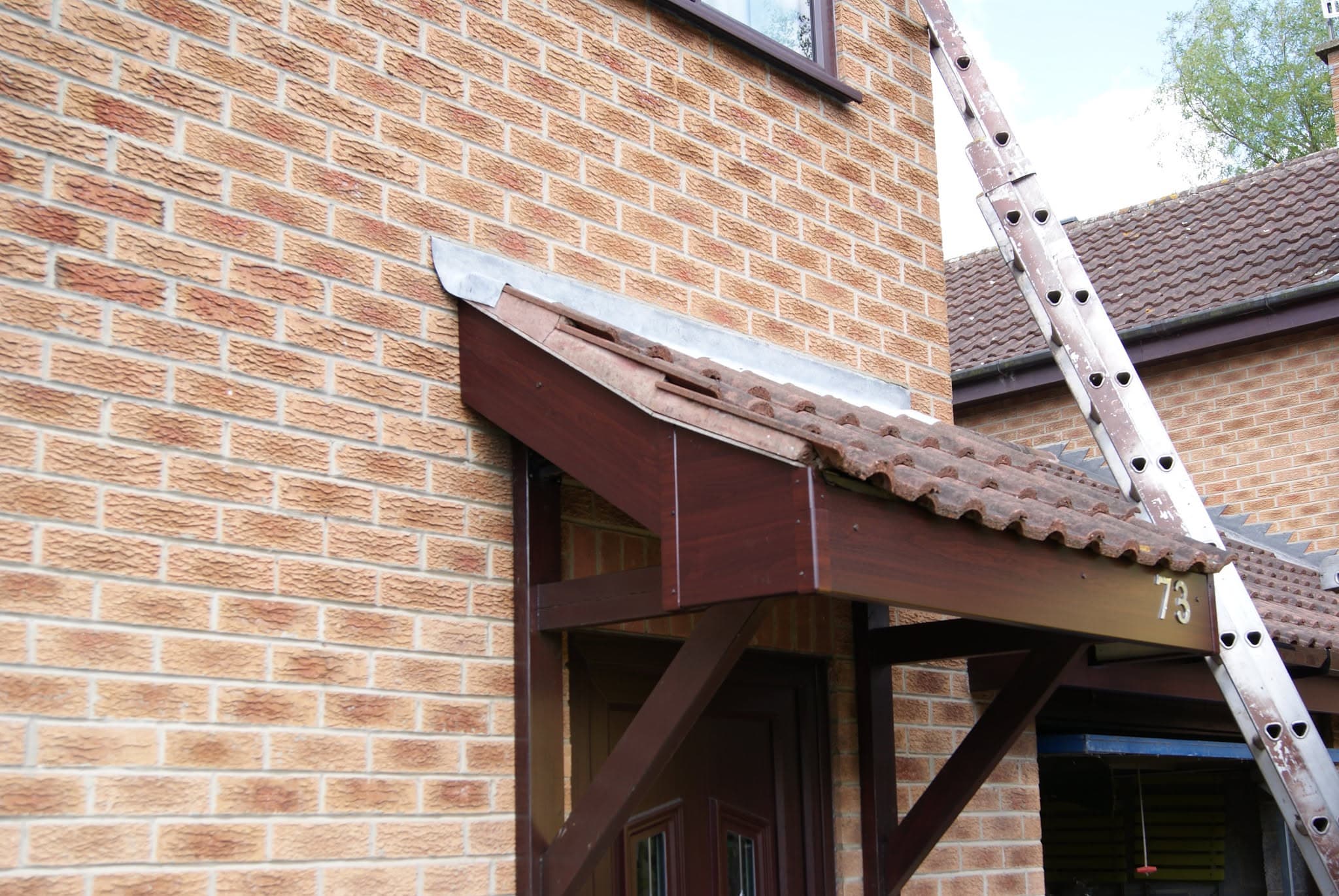 Tiled porch canopy with lead flashing against brick wall