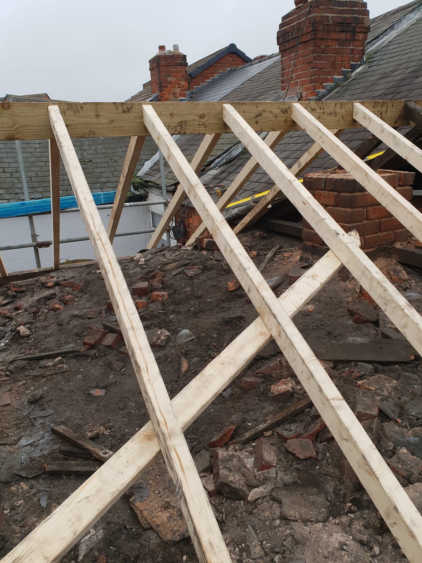 New timber roof structure under construction with exposed rafters and brick chimney stacks