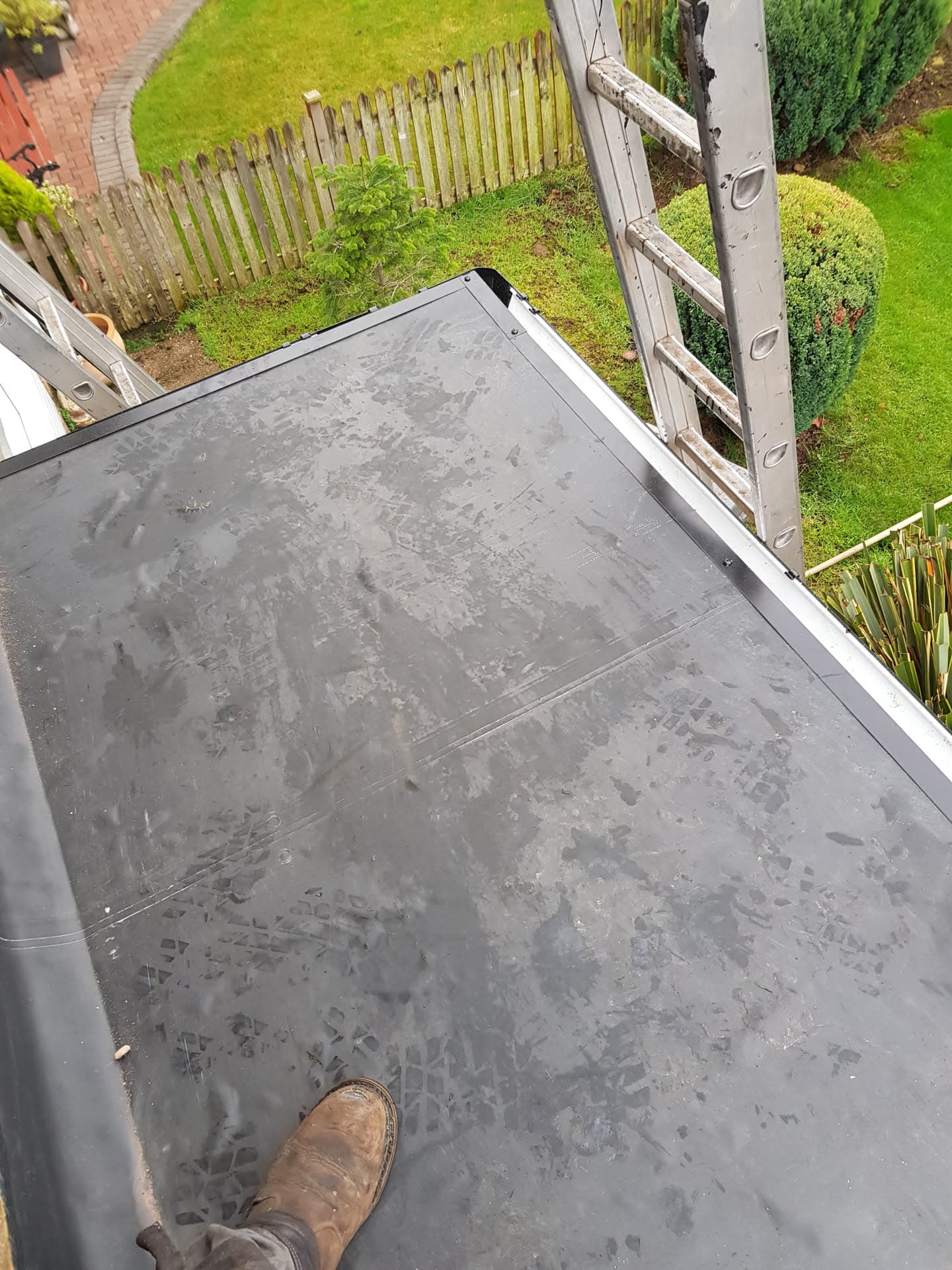 Grey flat roof with white fascia trim and ladder access to garden