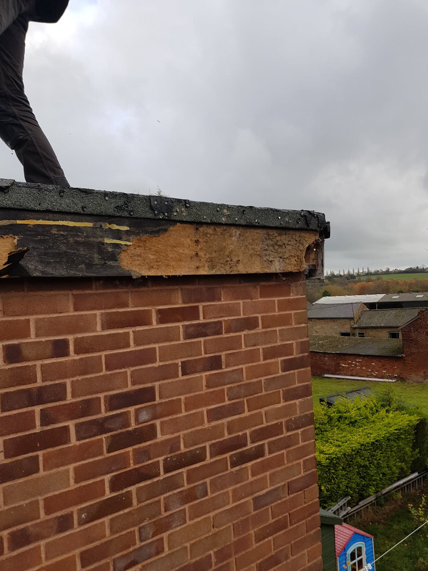 Damaged fascia board and roofline requiring repair on brick building
