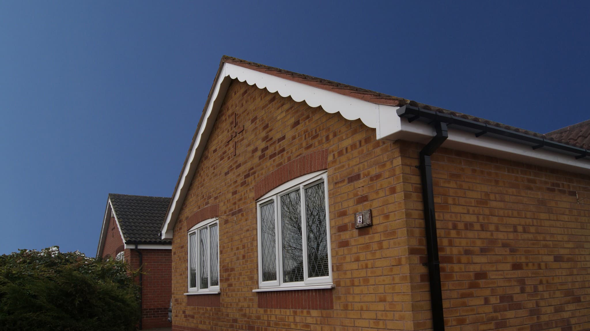 Pitched roof with red clay tiles, white decorative bargeboard and brown fascias and guttering
