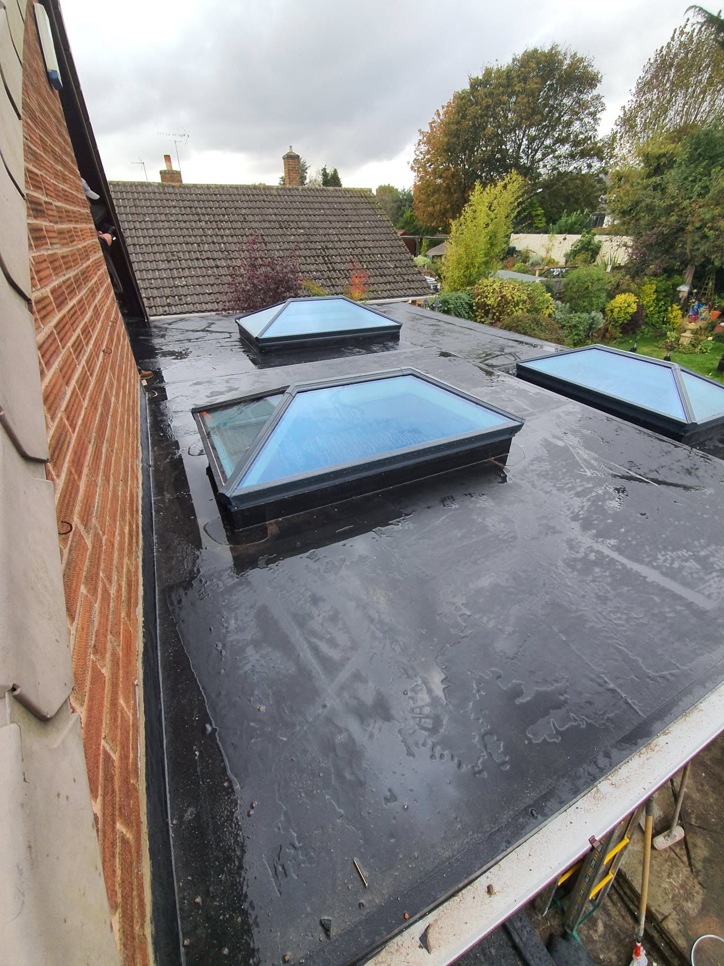 Flat roof with three glazed rooflights and dark grey felt covering