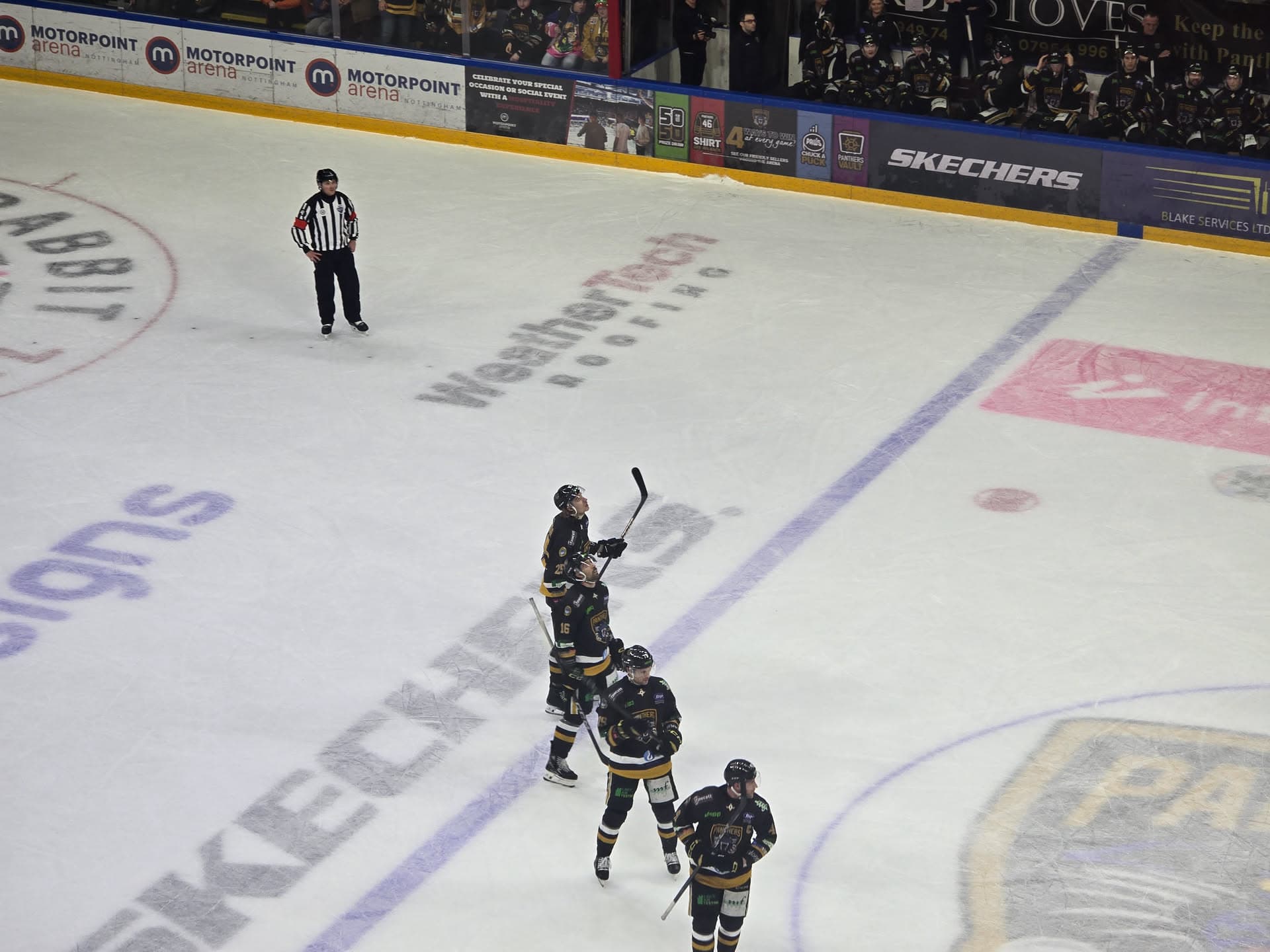 Nottingham Panthers players celebrating on the WeatherTech logo at the Motorpoint Arena