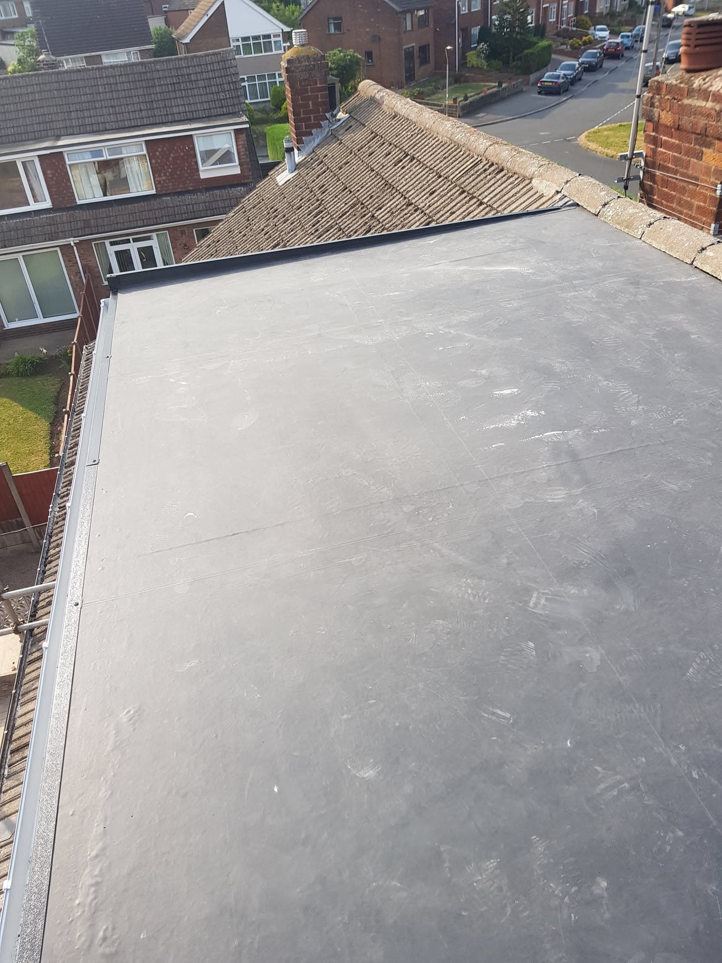 Grey flat roof extension with white fascias adjoining pitched tiled roof