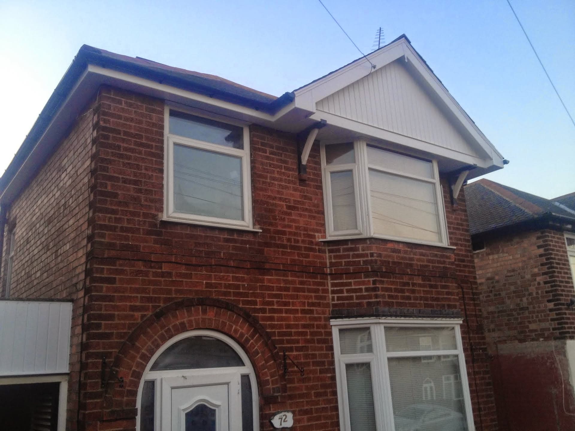 Red brick house with pitched roof, white fascias and soffits, and dark guttering
